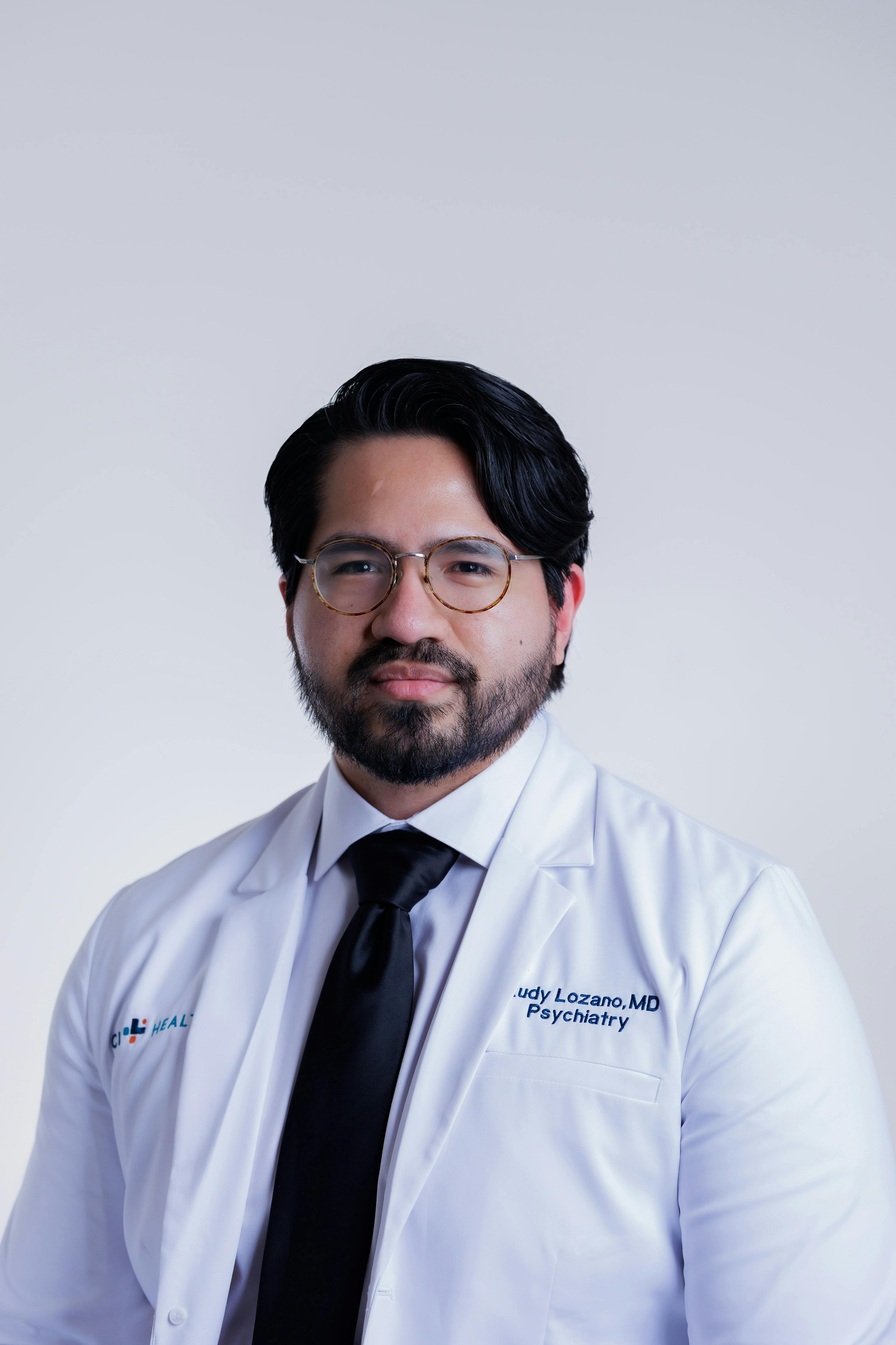 Rudy Lozano, MD, psychiatrist in Clear Lake posing for his headshot in his white coat. 