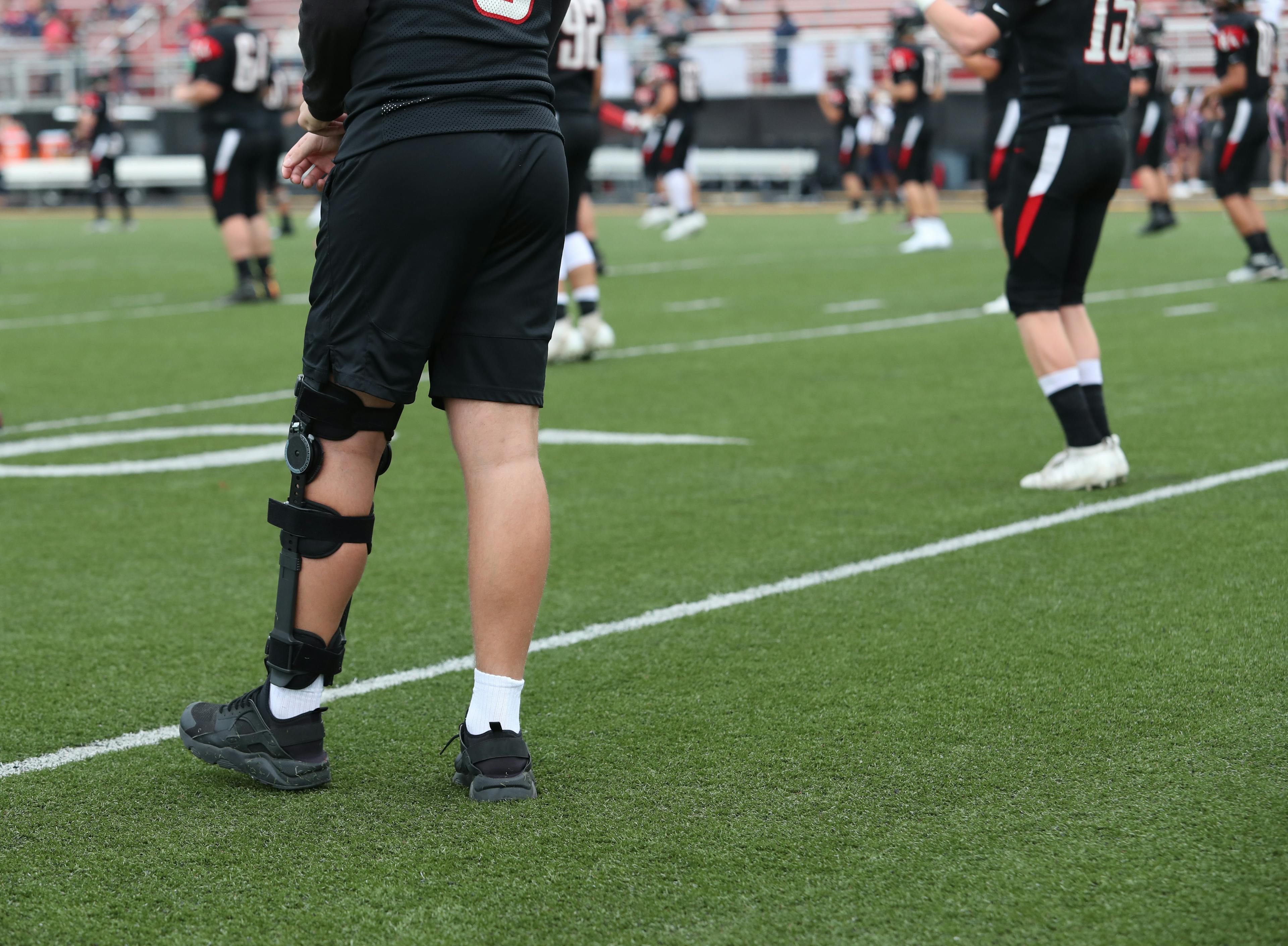 An injured player walks around as his teammates warm up.