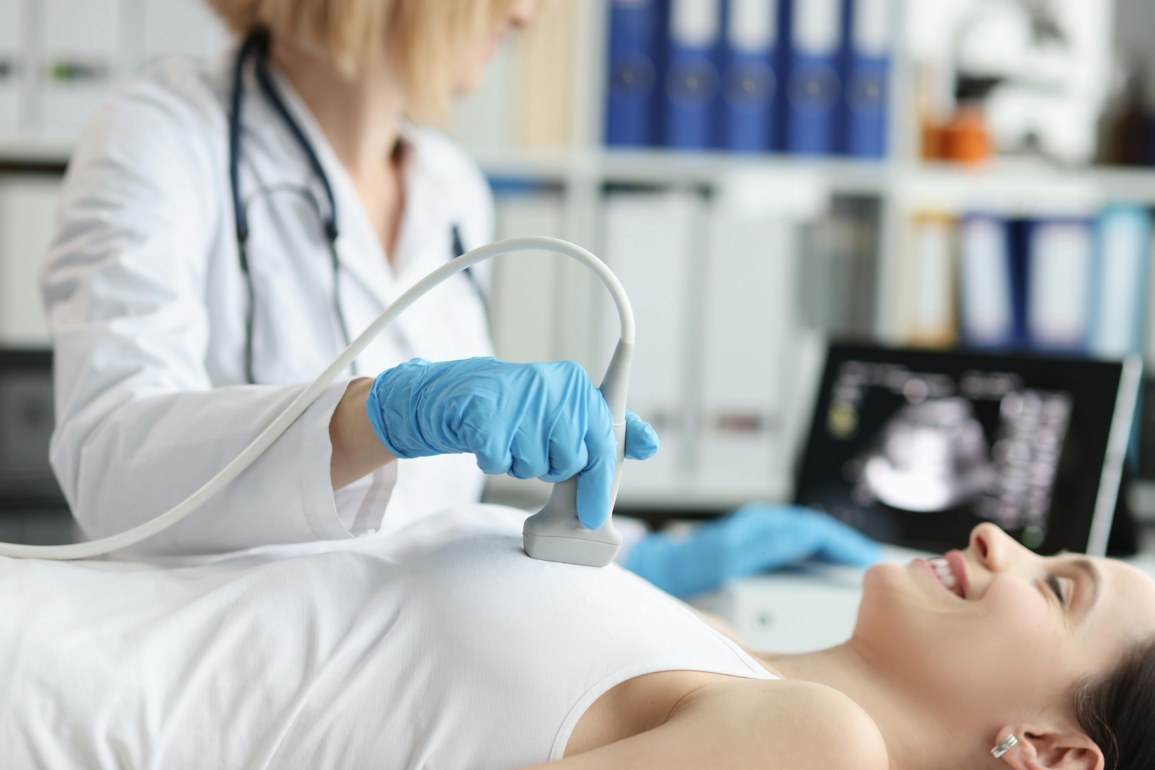 Doctor doing ultrasound examination of breast of patient in clinic.