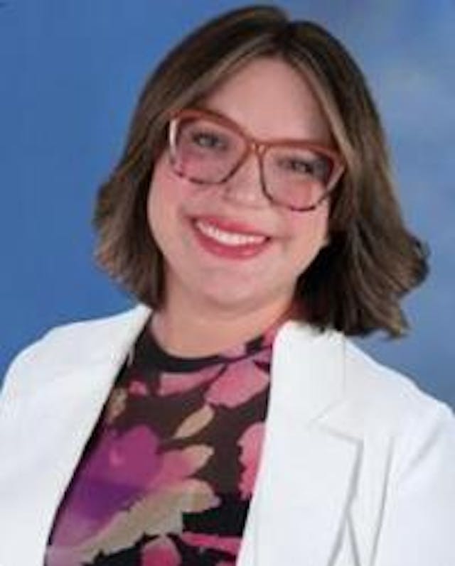 Christelle Reeves, DO, a Houston-based OB/GYN posing for her headshot in her white coat.