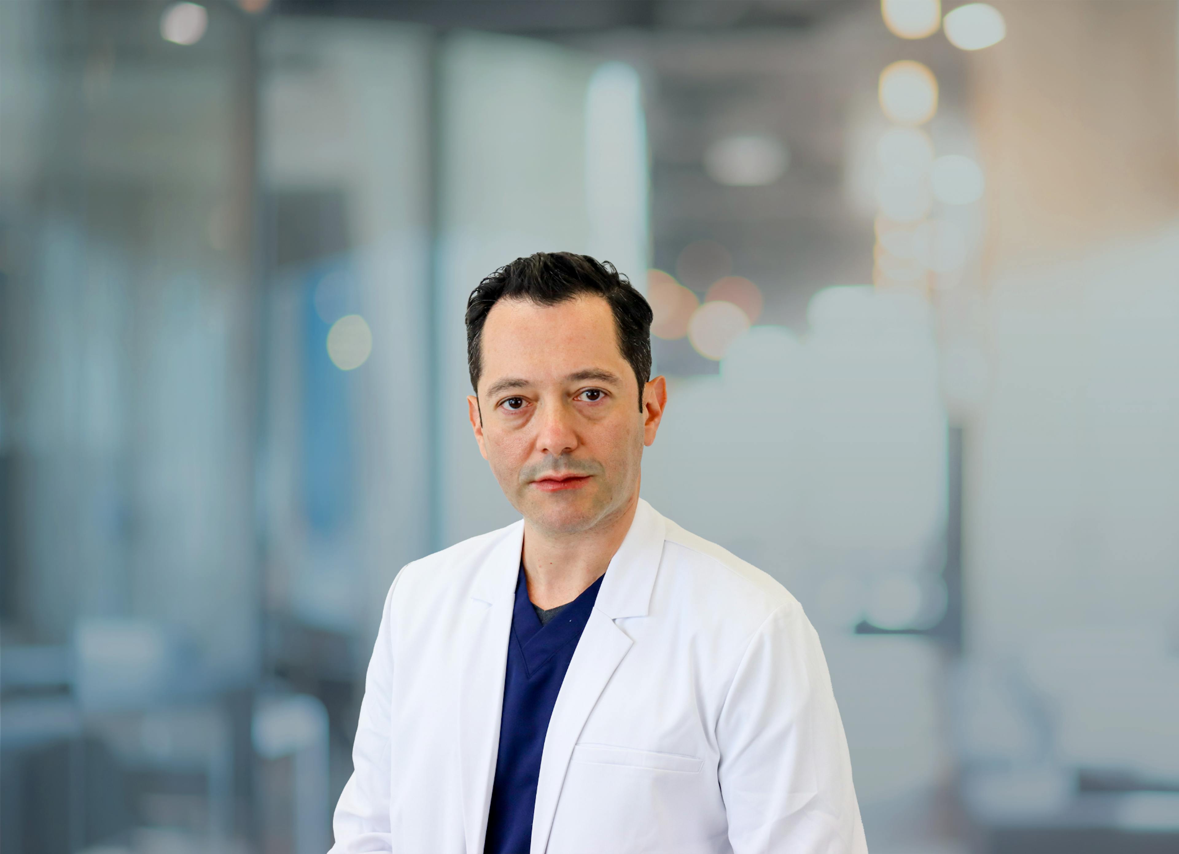 Yevgeny Shuhatovich, DO, pictured in his white coat for a headshot.