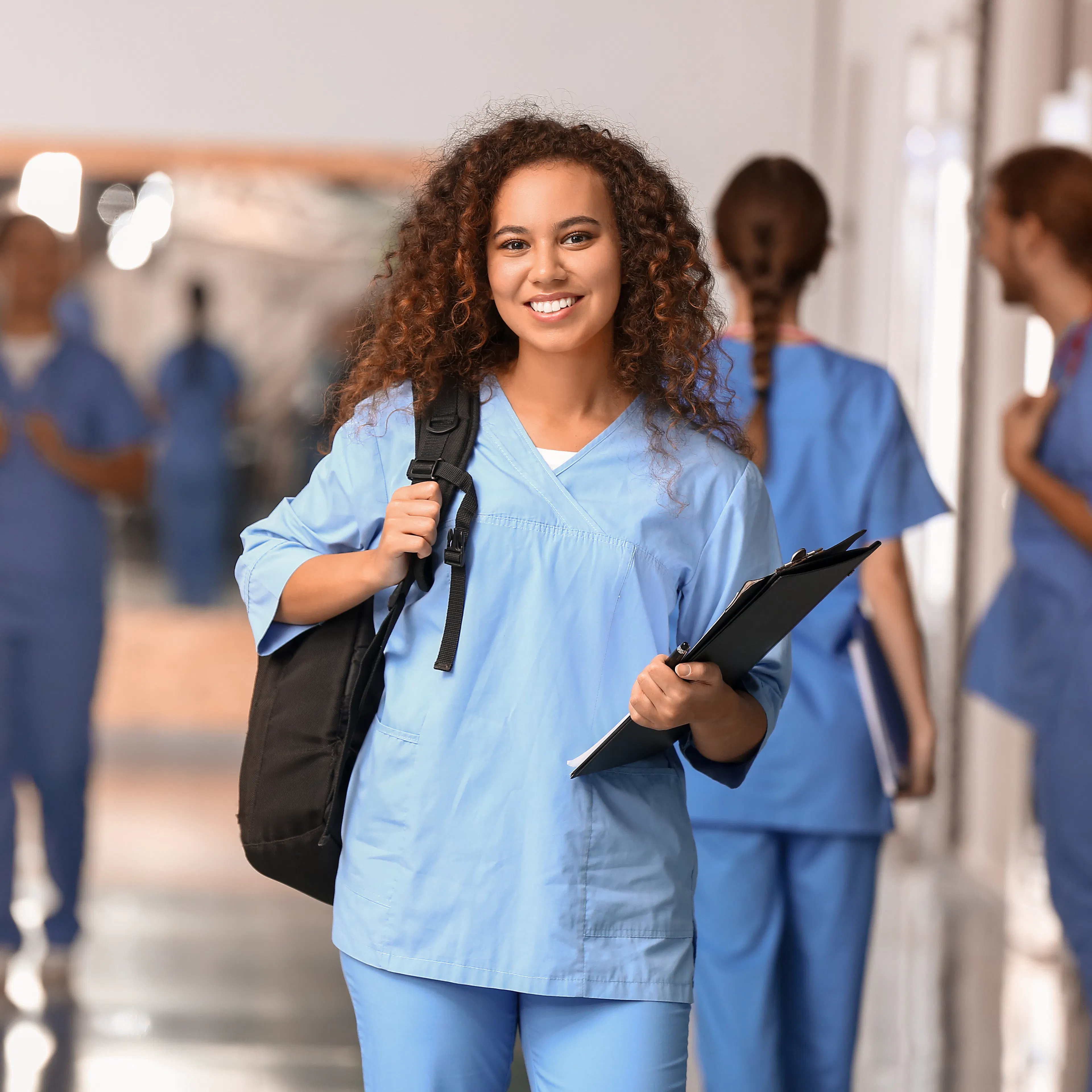 A female medical student is smiling with her backpack.