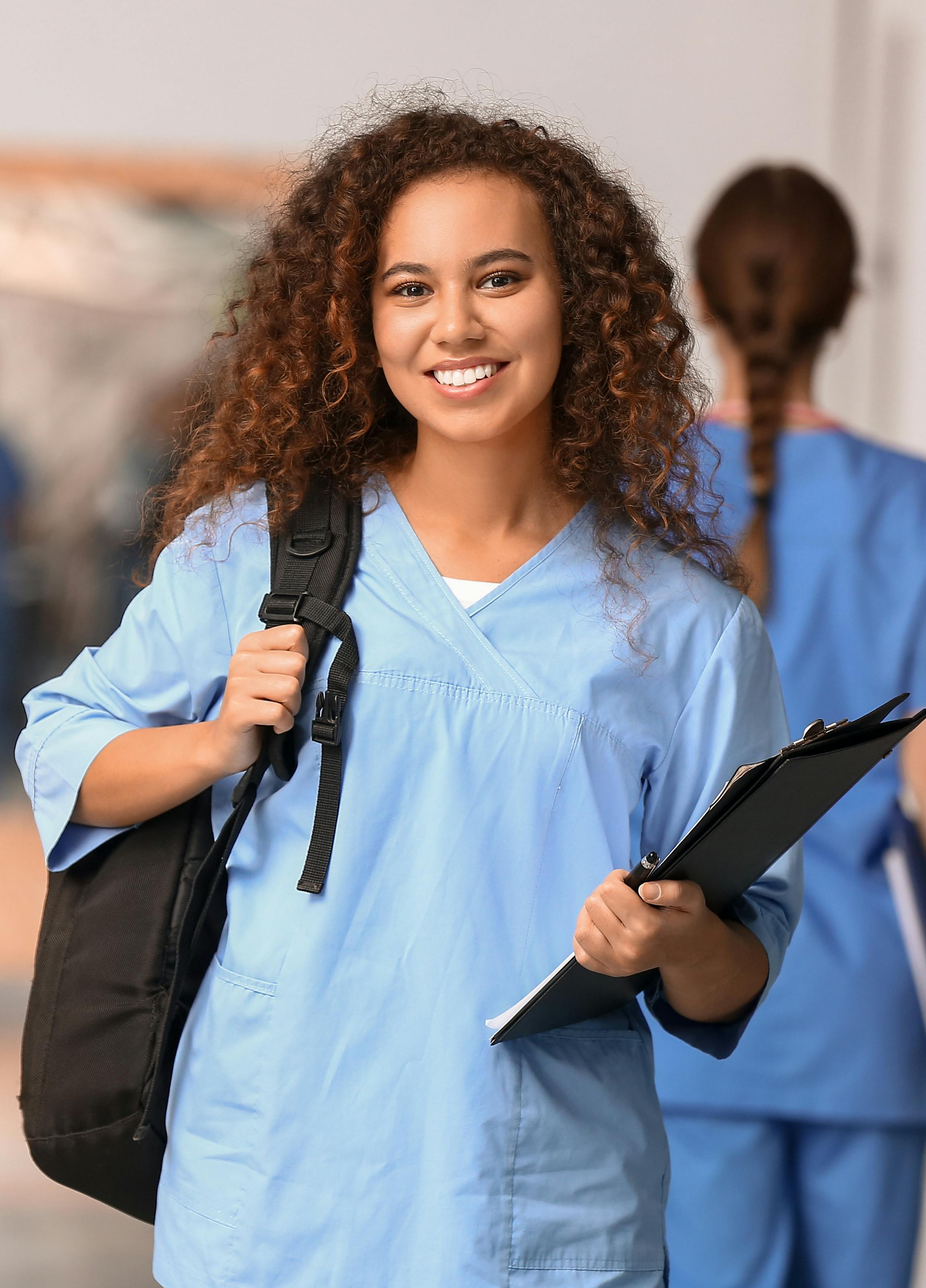 A female medical student is smiling with her backpack.