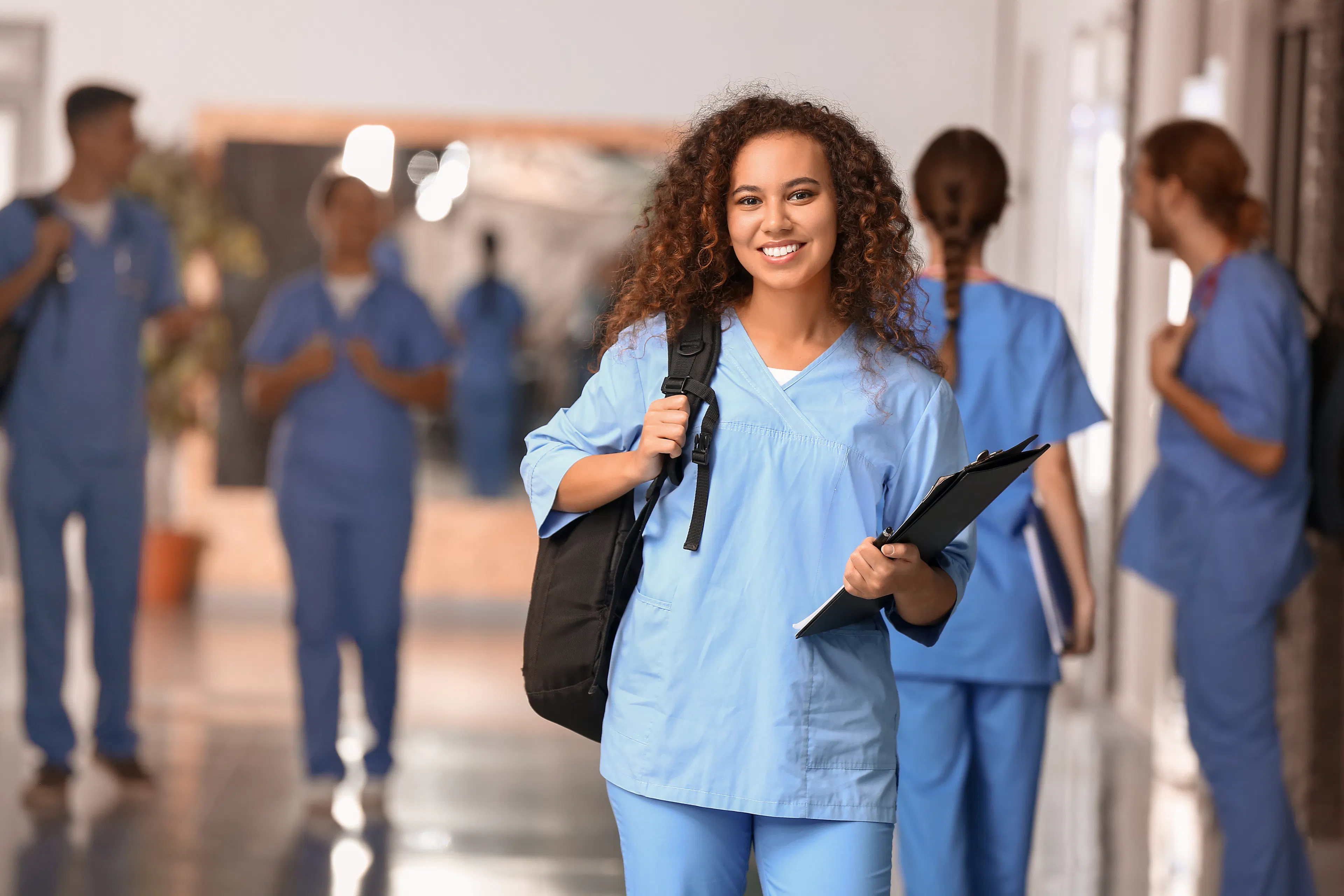 A female medical student is smiling with her backpack.