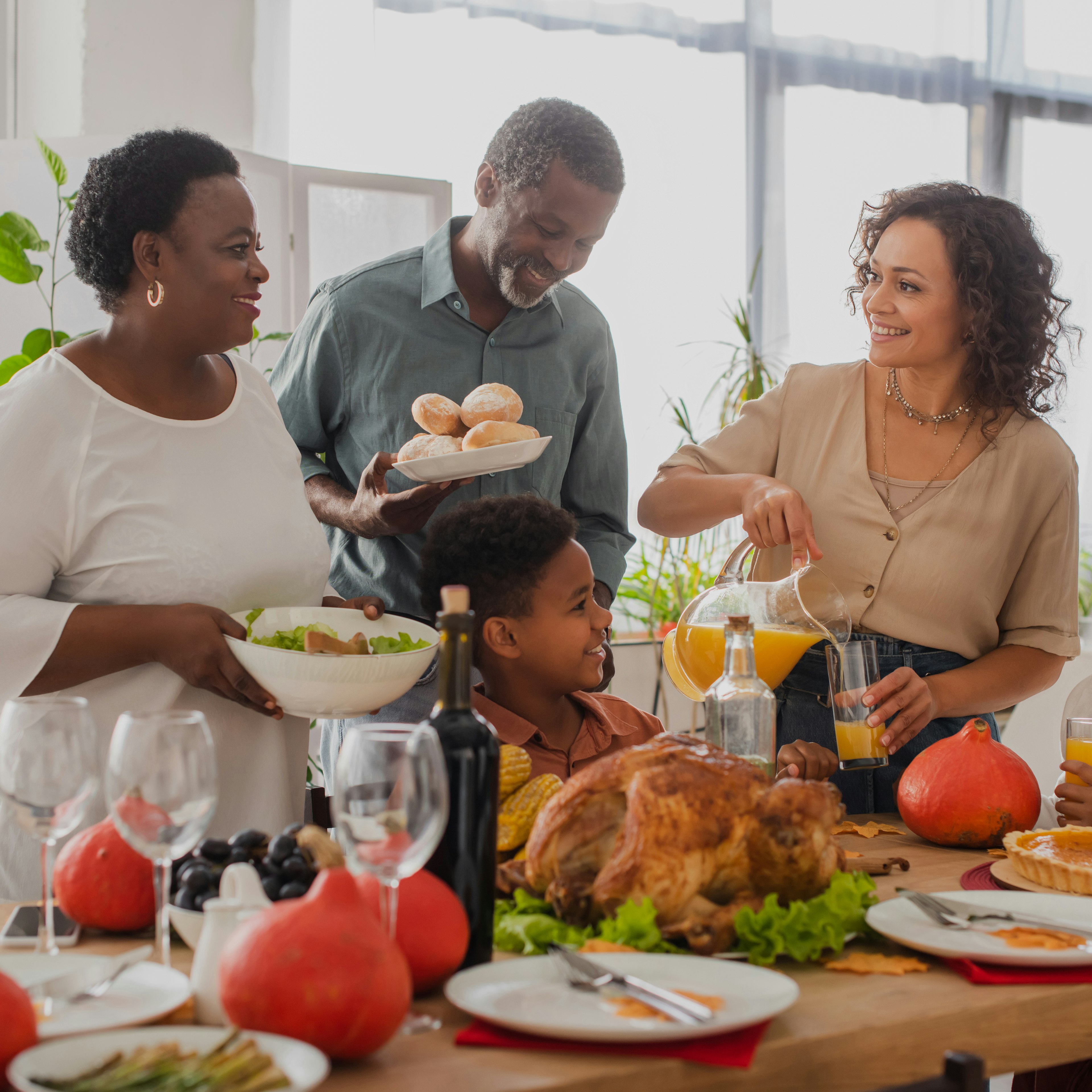 A family is enjoying a Thanksgiving feast together, with traditional dishes for the holiday spread across the table.