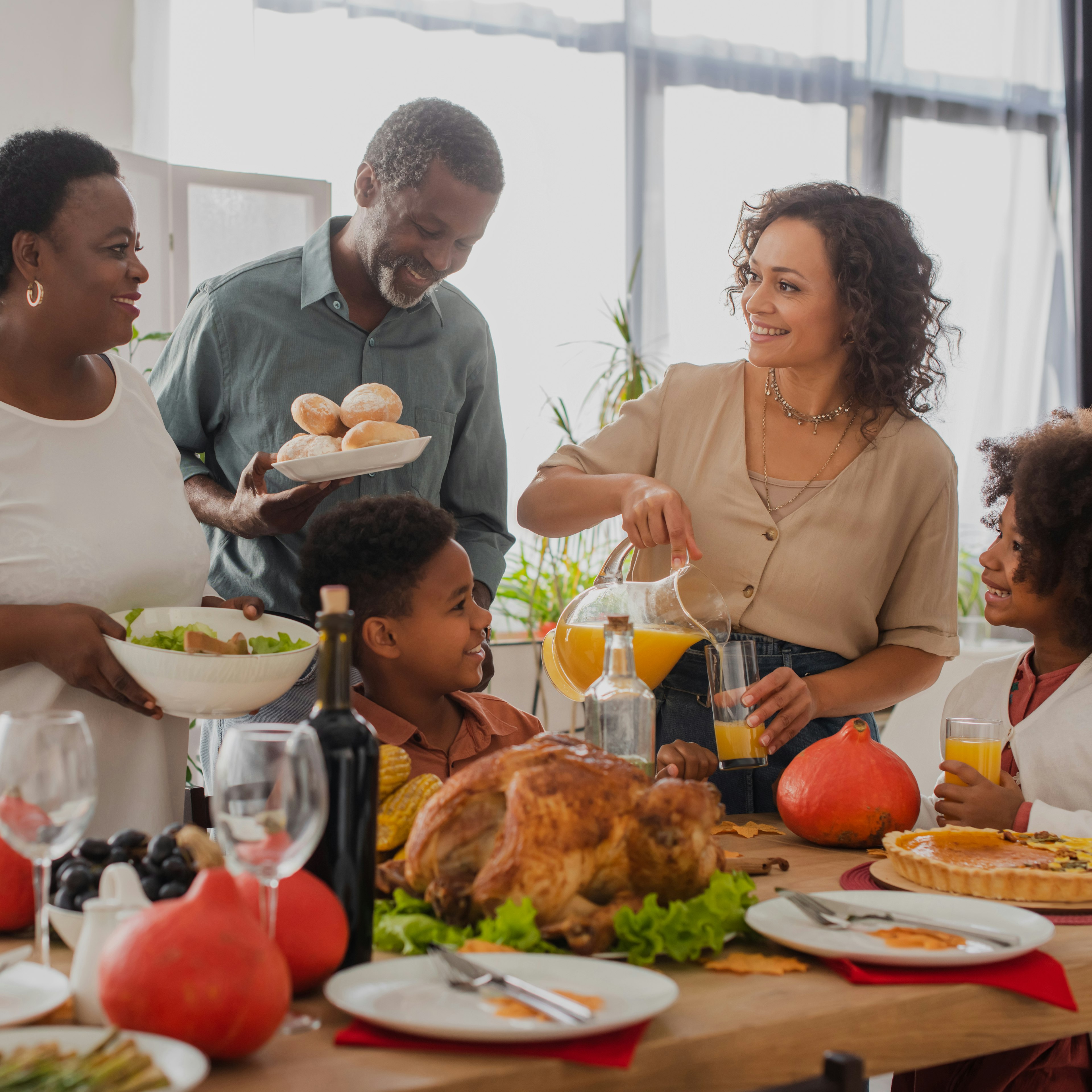 A family is enjoying a Thanksgiving feast together, with traditional dishes for the holiday spread across the table.