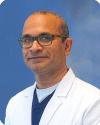 Cardiac electrophysiologist, Harsha Ganga, posing for his headshot in his white coat.