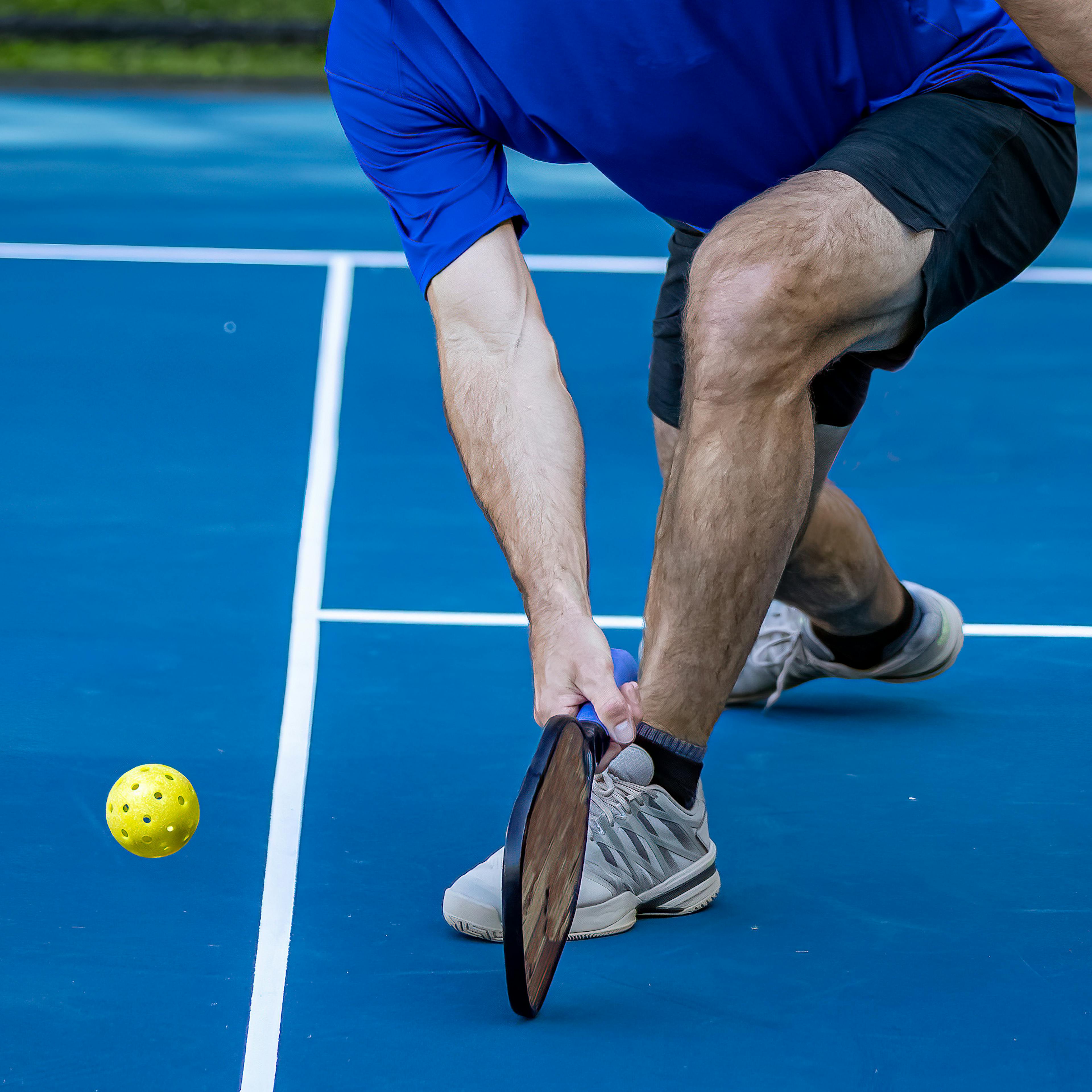 A man playing pickleball outdoors on a court.