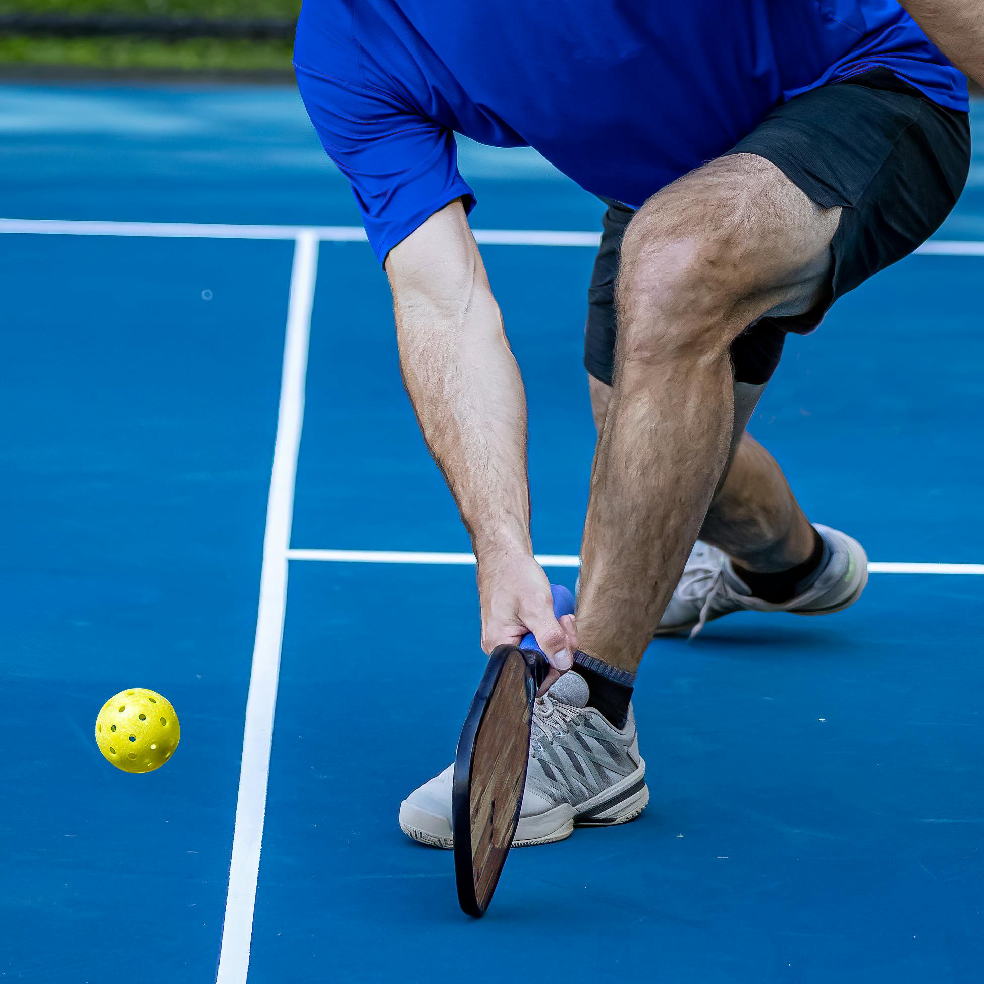 A man playing pickleball outdoors on a court.