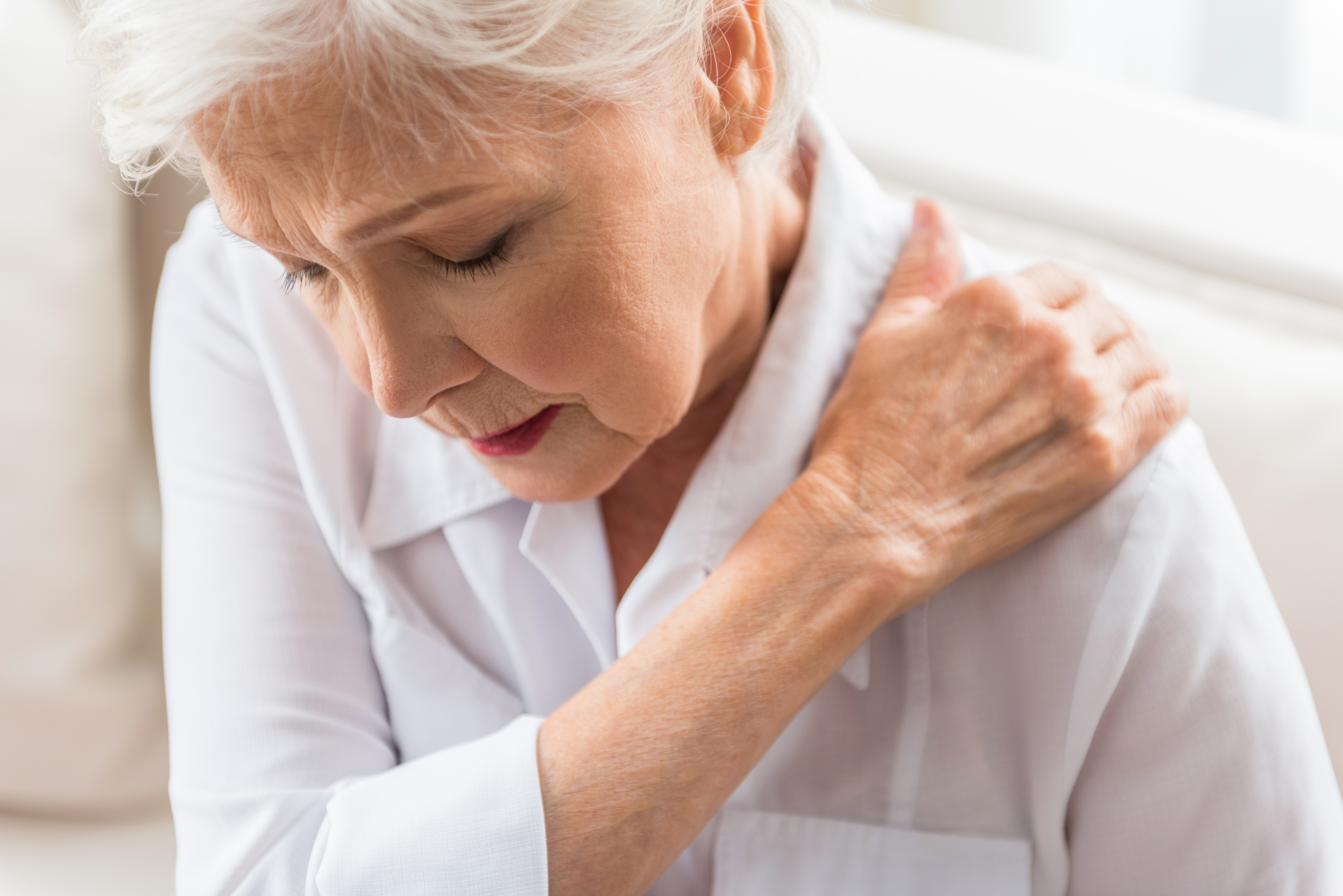 An elderly woman is experiencing shoulder pain.