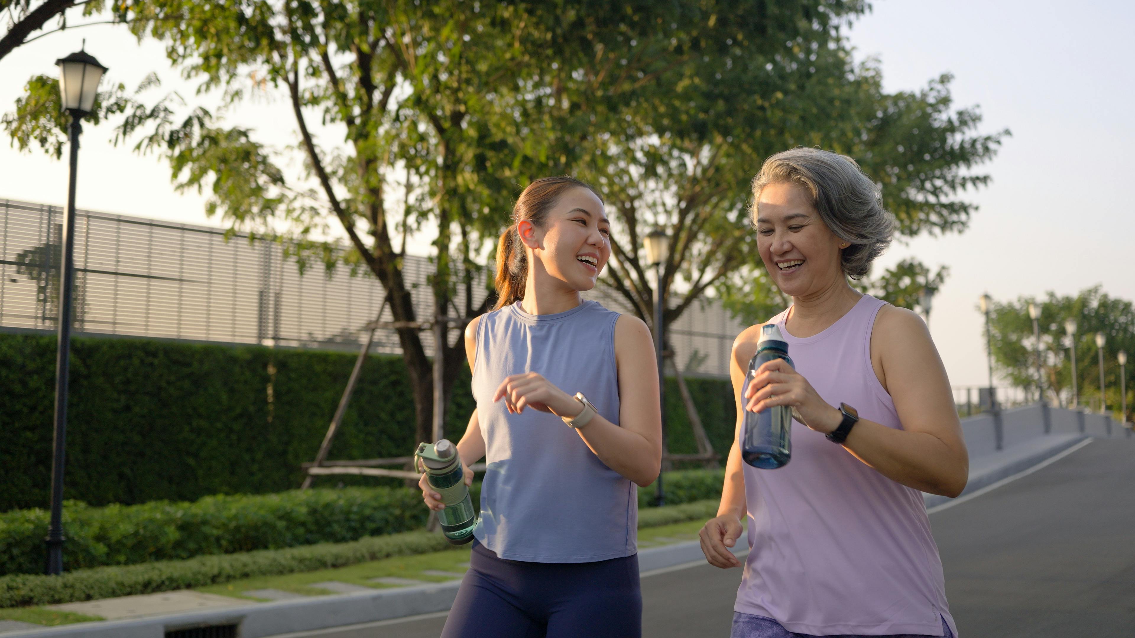 A young woman and an older woman walk and converse together while smiling