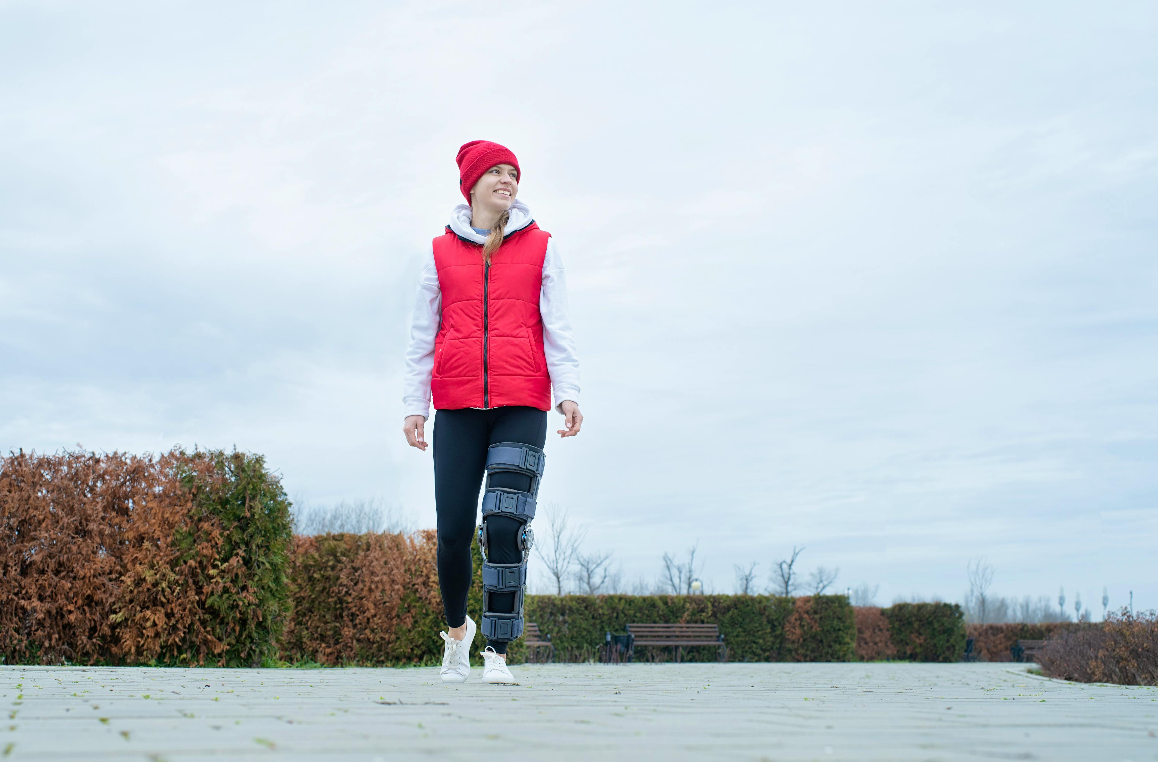 Person walking outdoors while wearing a knee brace, representing recovery and restoration after ACL surgery.