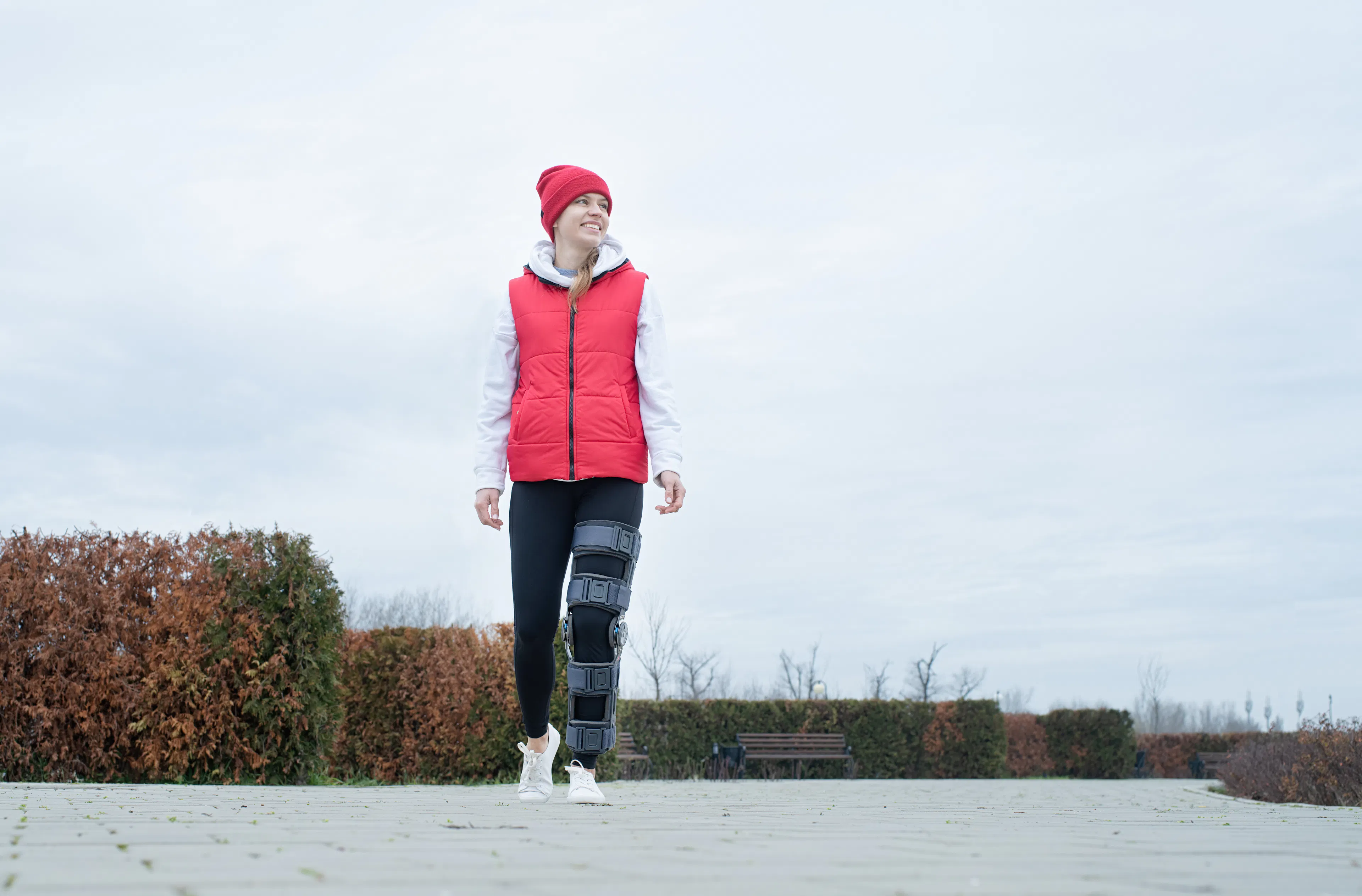 Person walking outdoors while wearing a knee brace, representing recovery and restoration after ACL surgery.