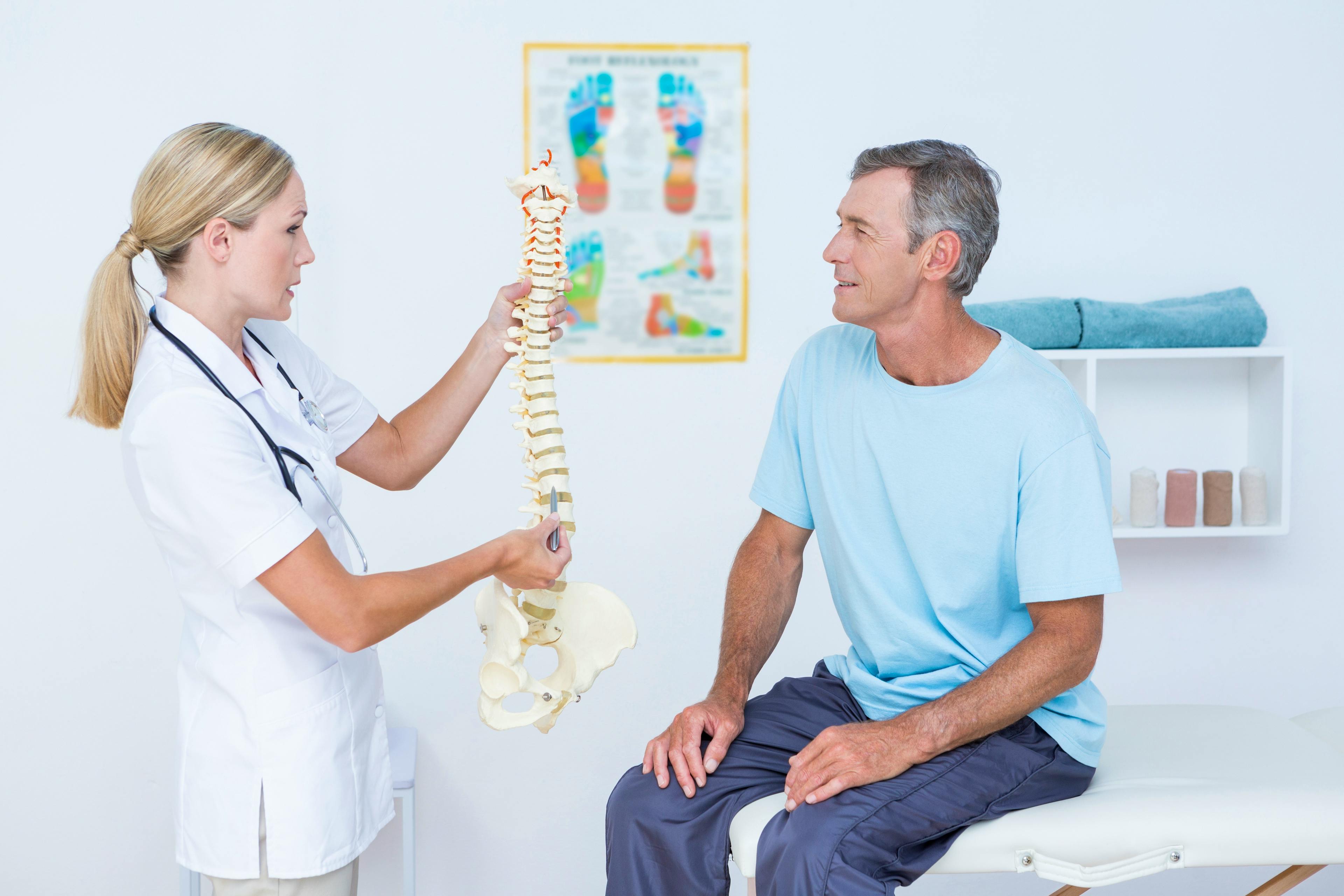 Healthcare provider explaining the spine to a patient using an anatomical model.