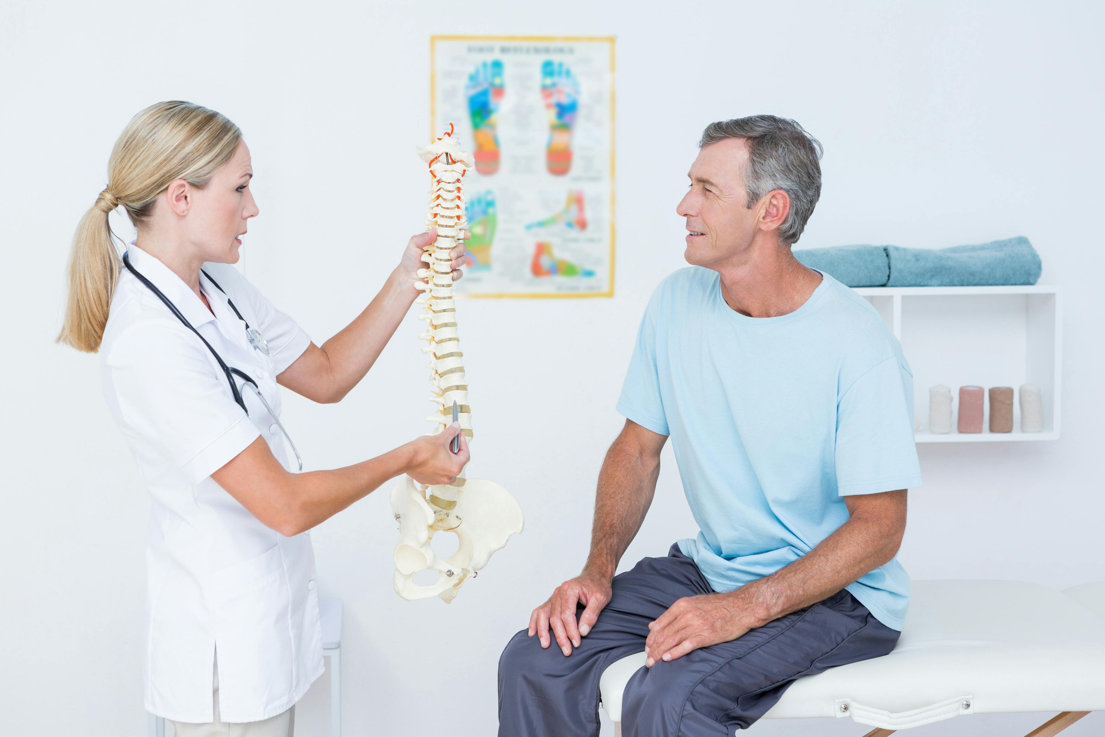 Healthcare provider explaining the spine to a patient using an anatomical model.