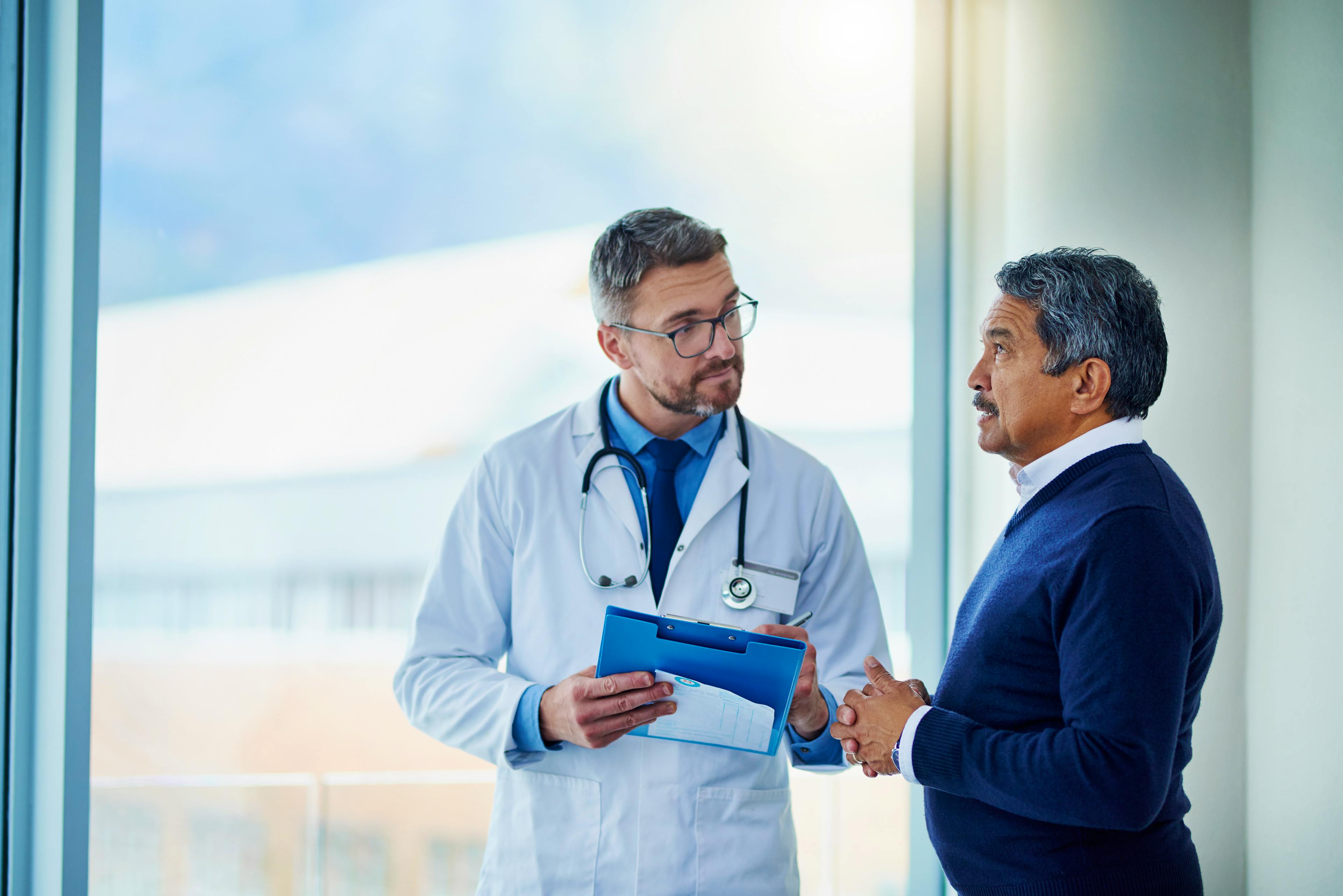 Doctor discussing a health concern with an older male patient in a medical office.