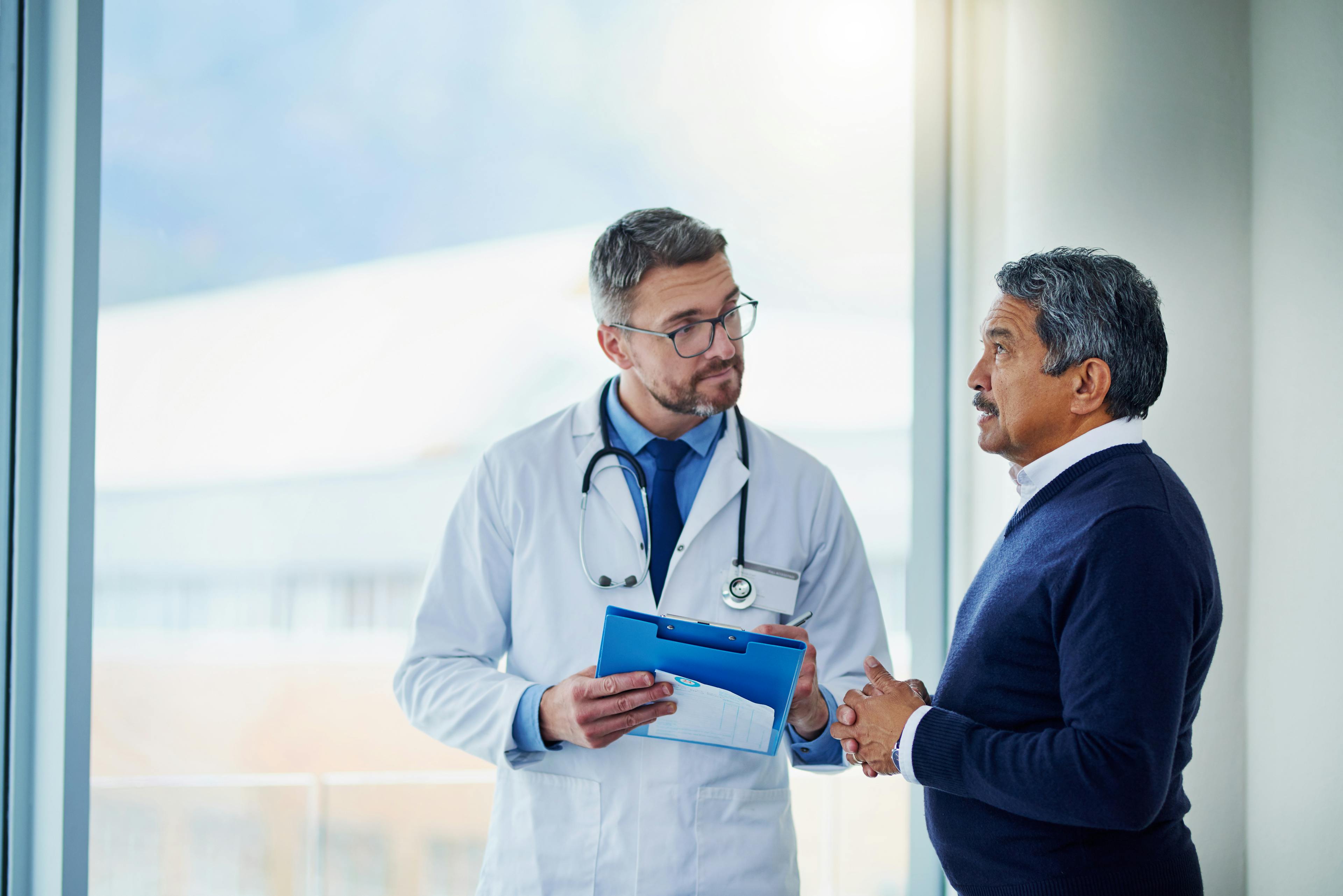 Doctor discussing a health concern with an older male patient in a medical office.