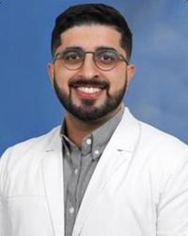 Imran Qureshi, DO, pain medicine physician posing for his headshot in his white coat. 