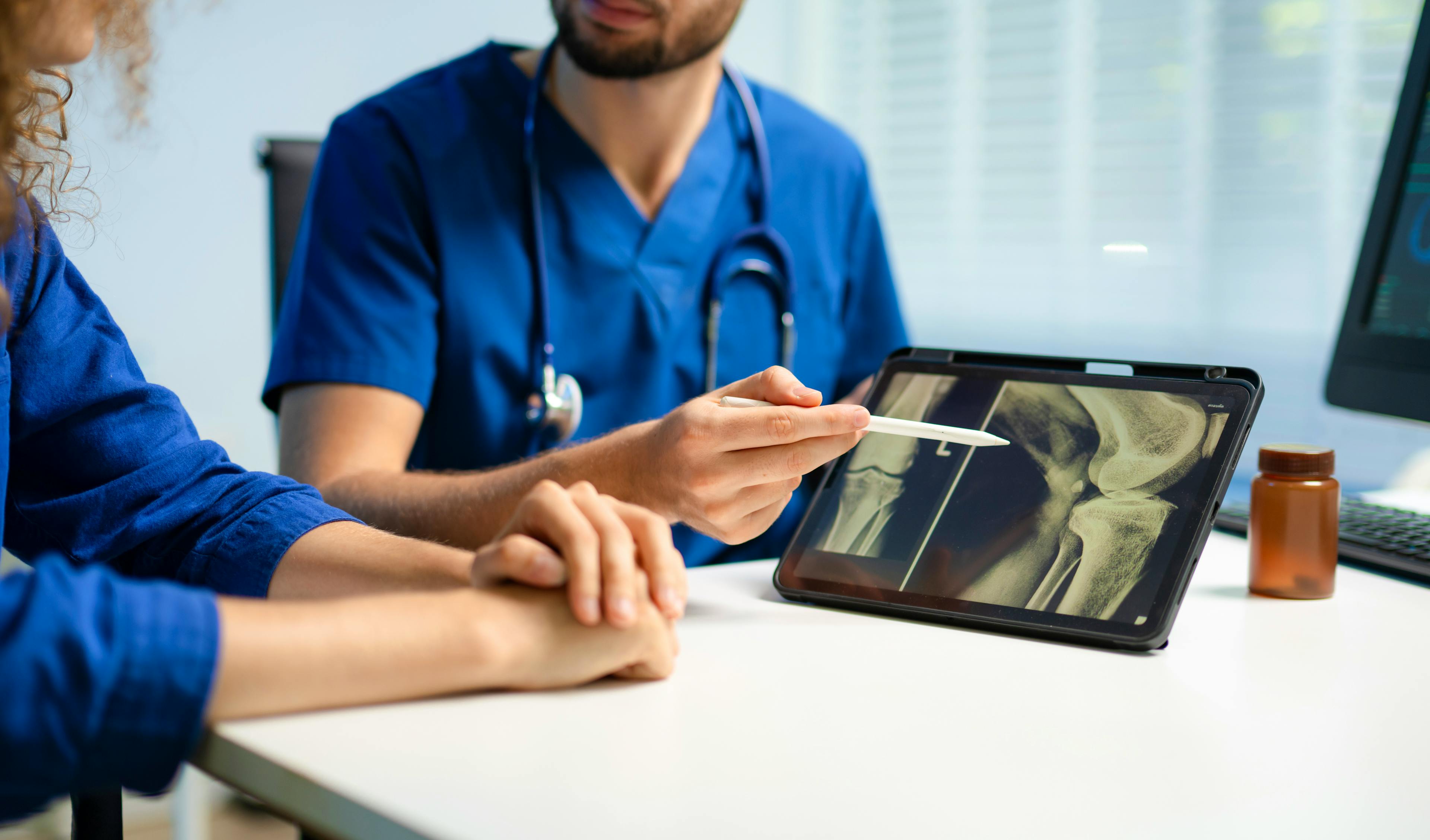 Doctor discussing joint imaging with a patient in a medical office.