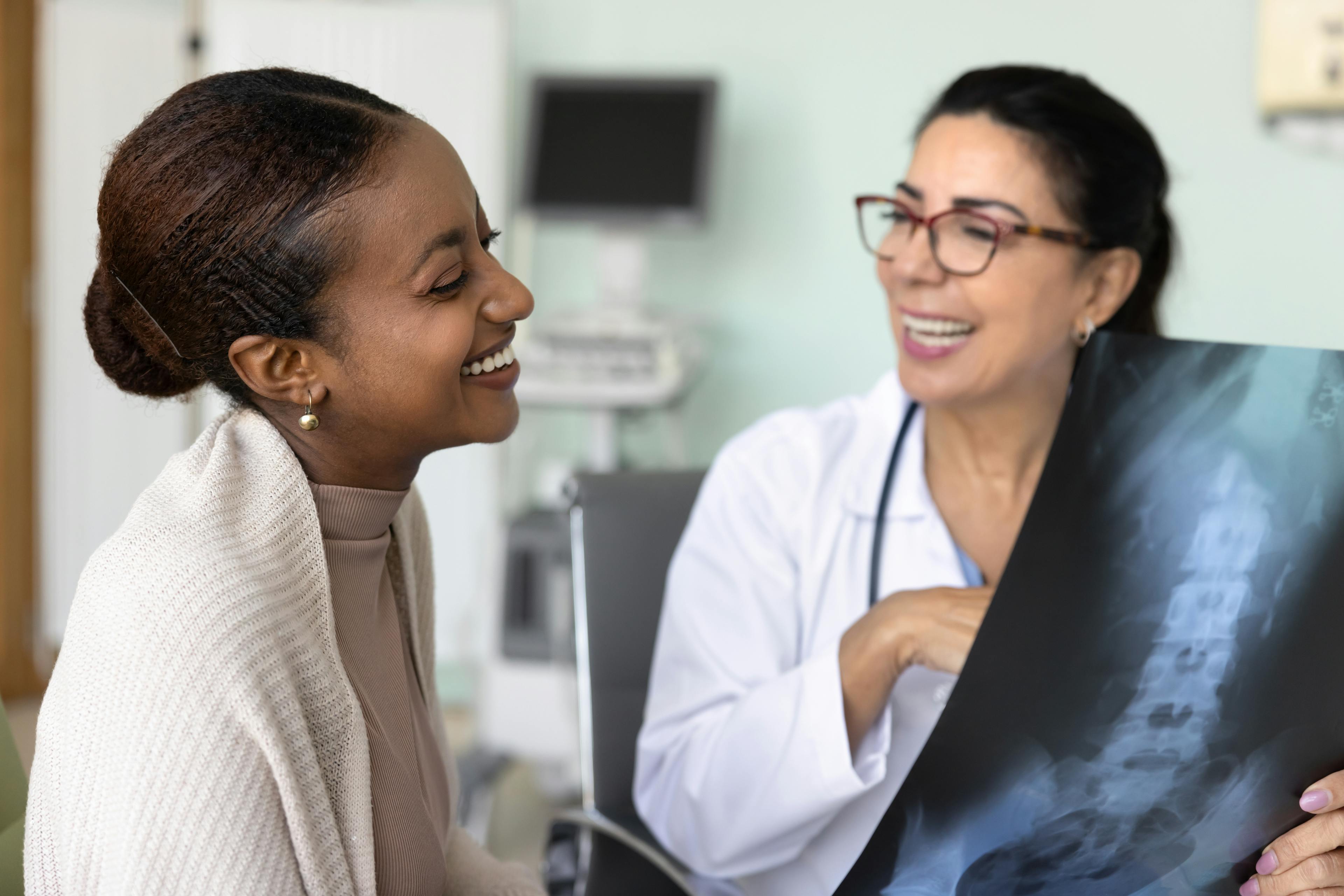 Clinician and patient smiling together while reviewing an X-ray image during a medical appointment.