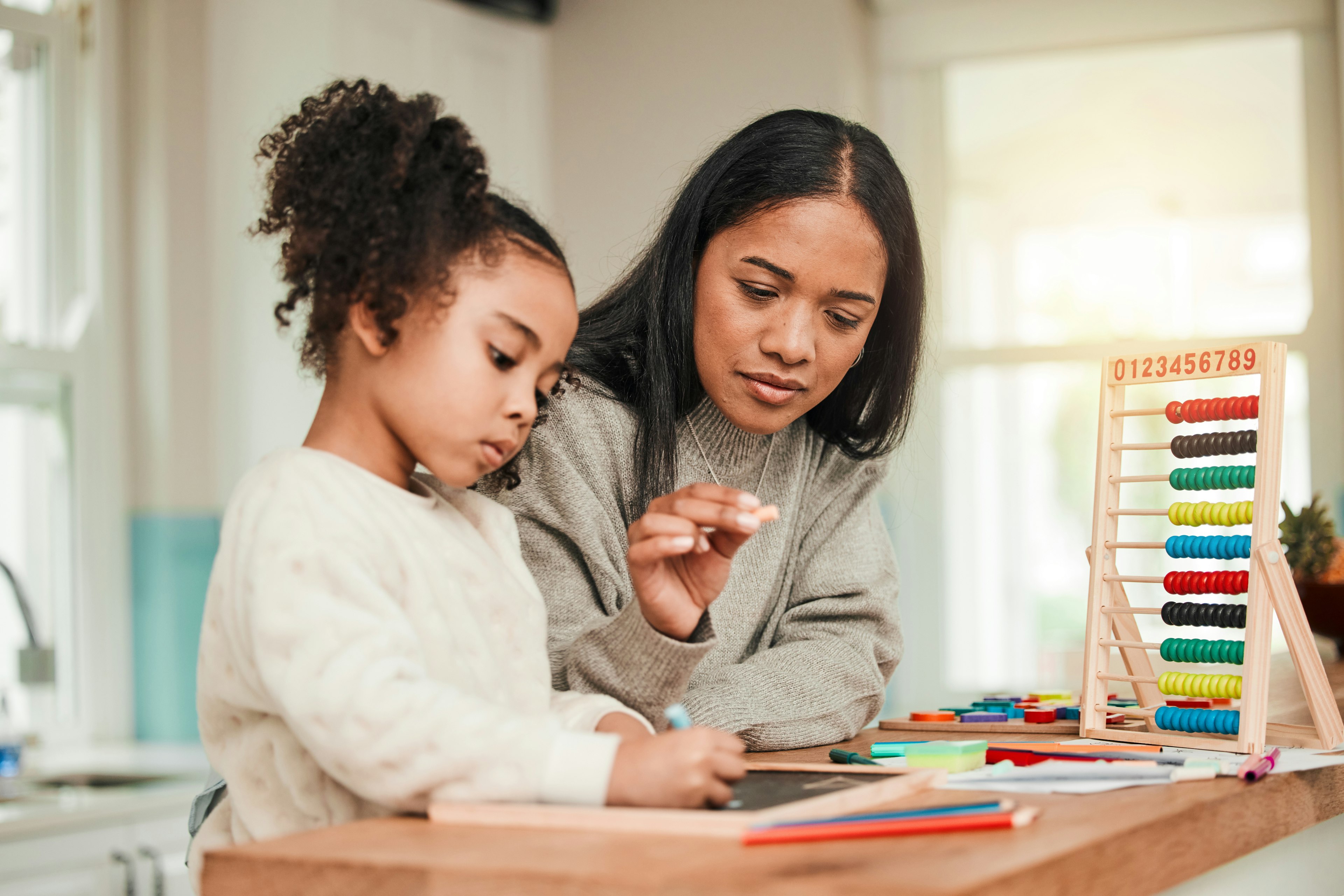 Parent helping child with homework at a table in a calm home setting
