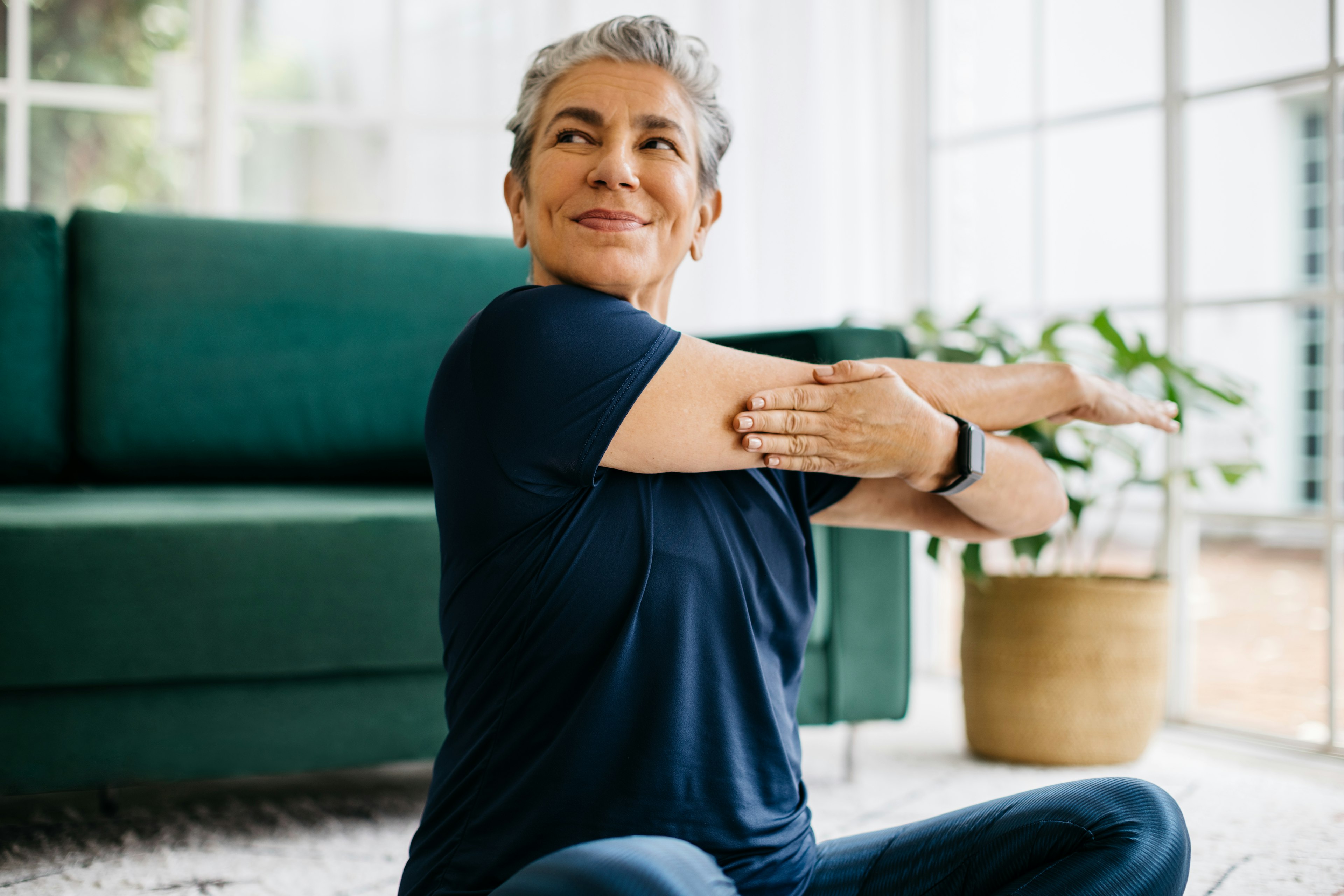 Adult performing a gentle shoulder stretch at home as part of at-home shoulder pain relief.
