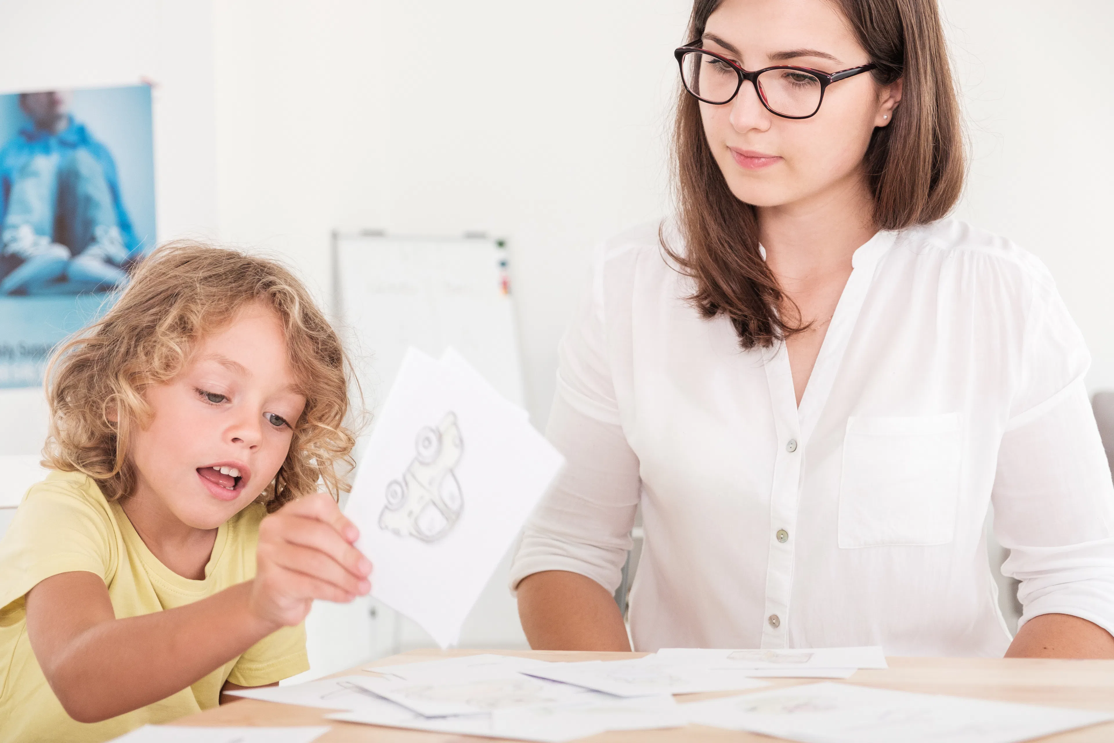 Clinician observing a child as they complete a developmental assessment activity using picture cards.