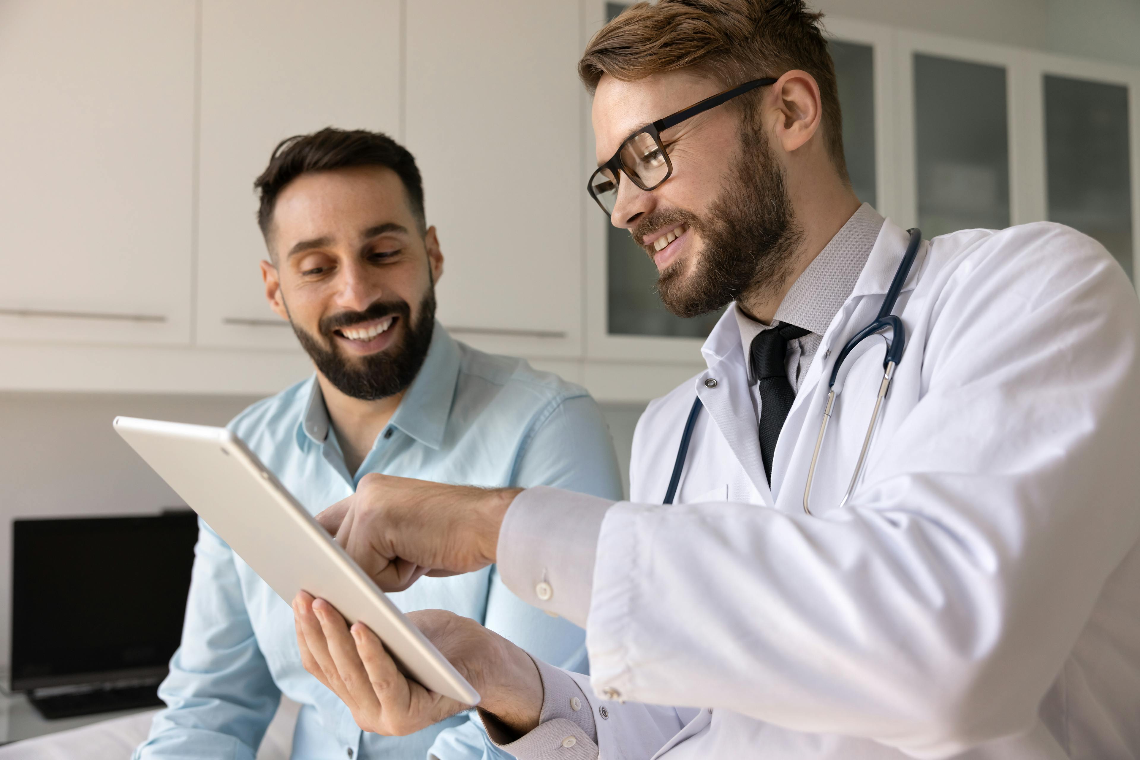 Doctor reviewing information on a tablet with a patient during a consultation in a medical office.