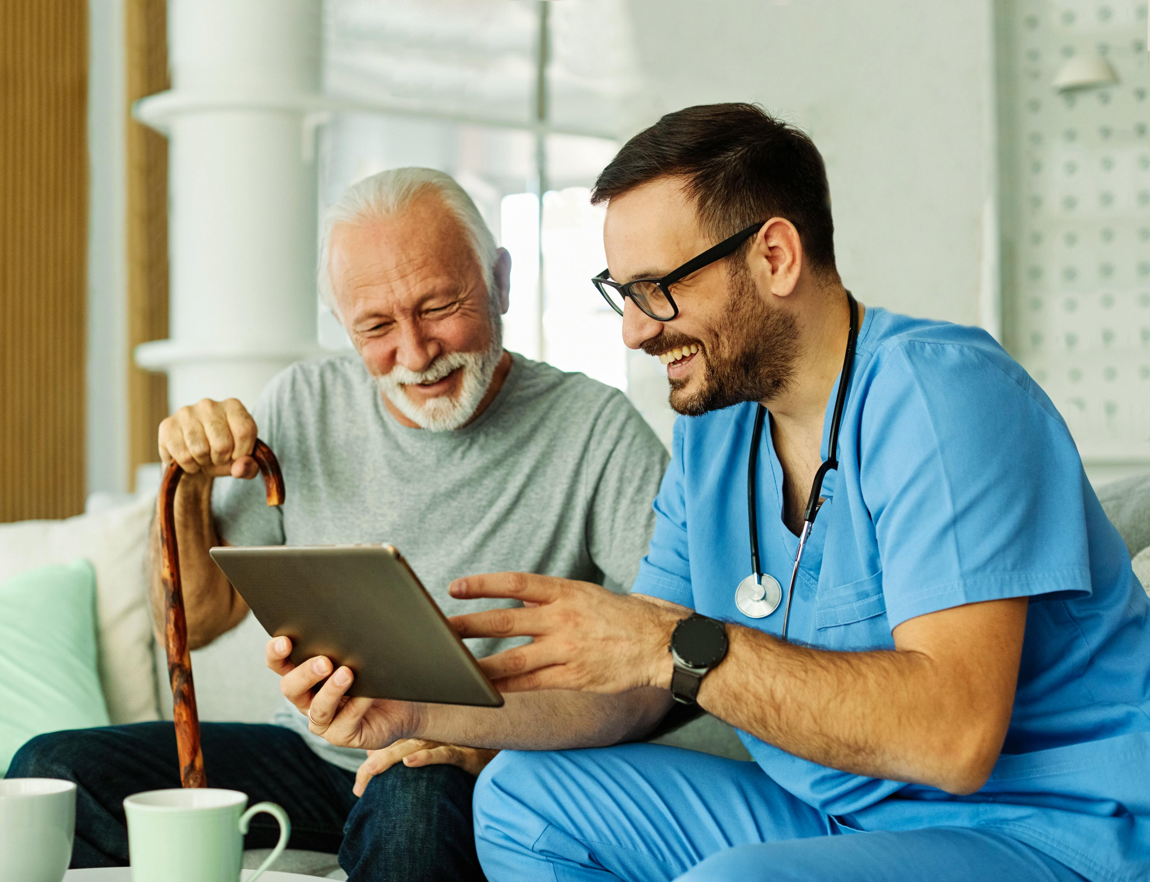 Healthcare provider reviewing information on a tablet with an older male patient during a medical consultation.