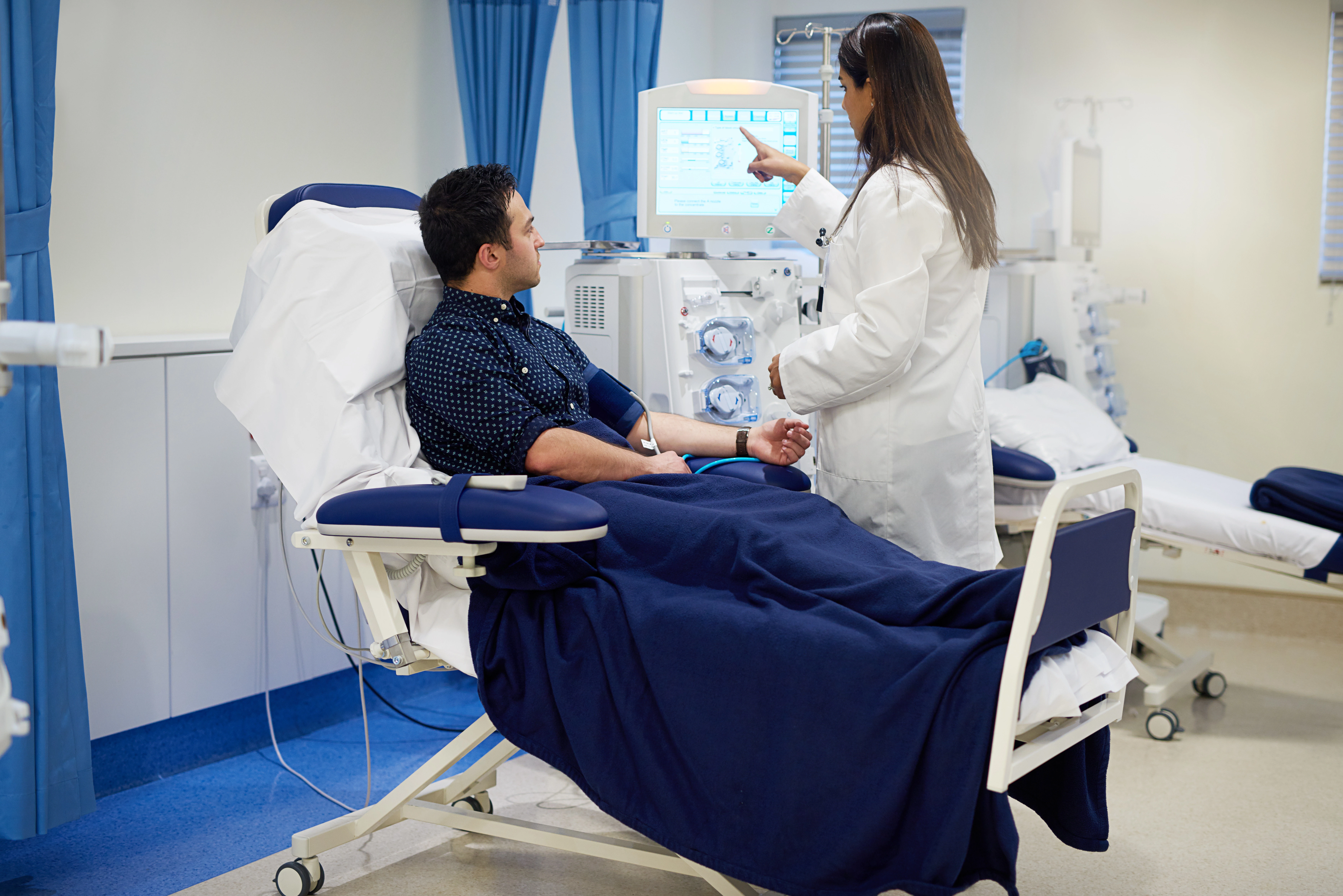 A nephrologist educating her patient as he goes through hemodialysis.