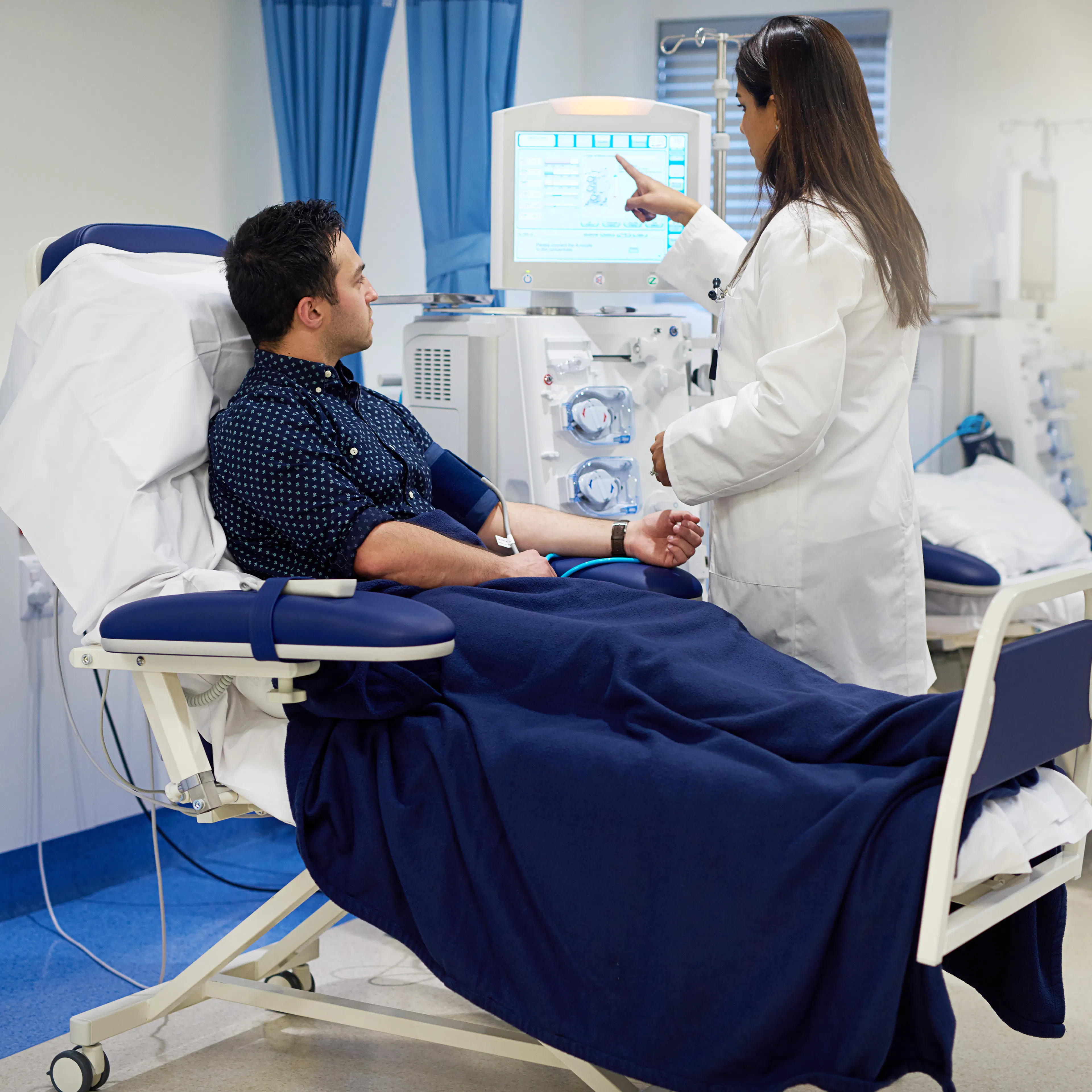 A nephrologist educating her patient as he goes through hemodialysis.
