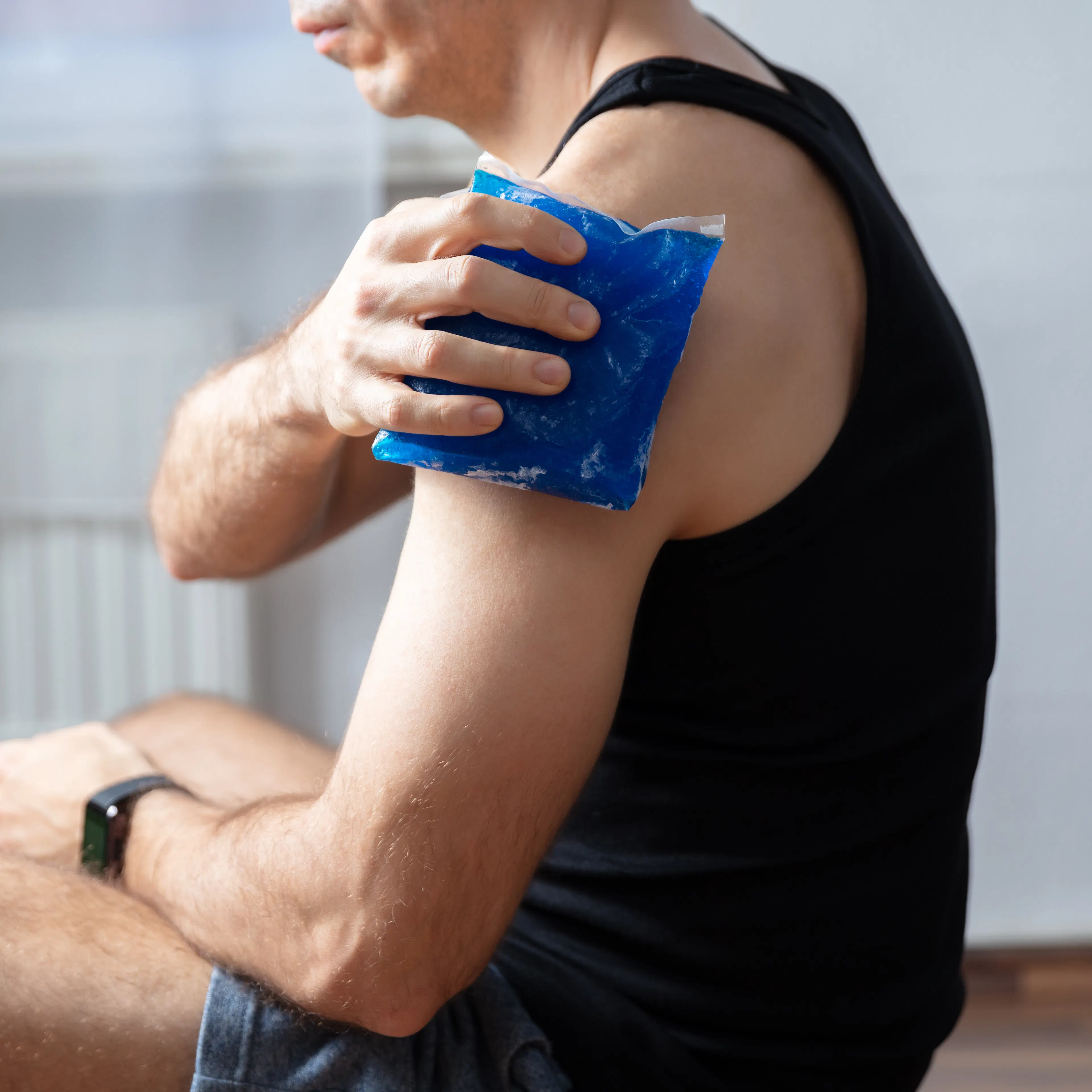 A man is icing his injury on his upper arm.