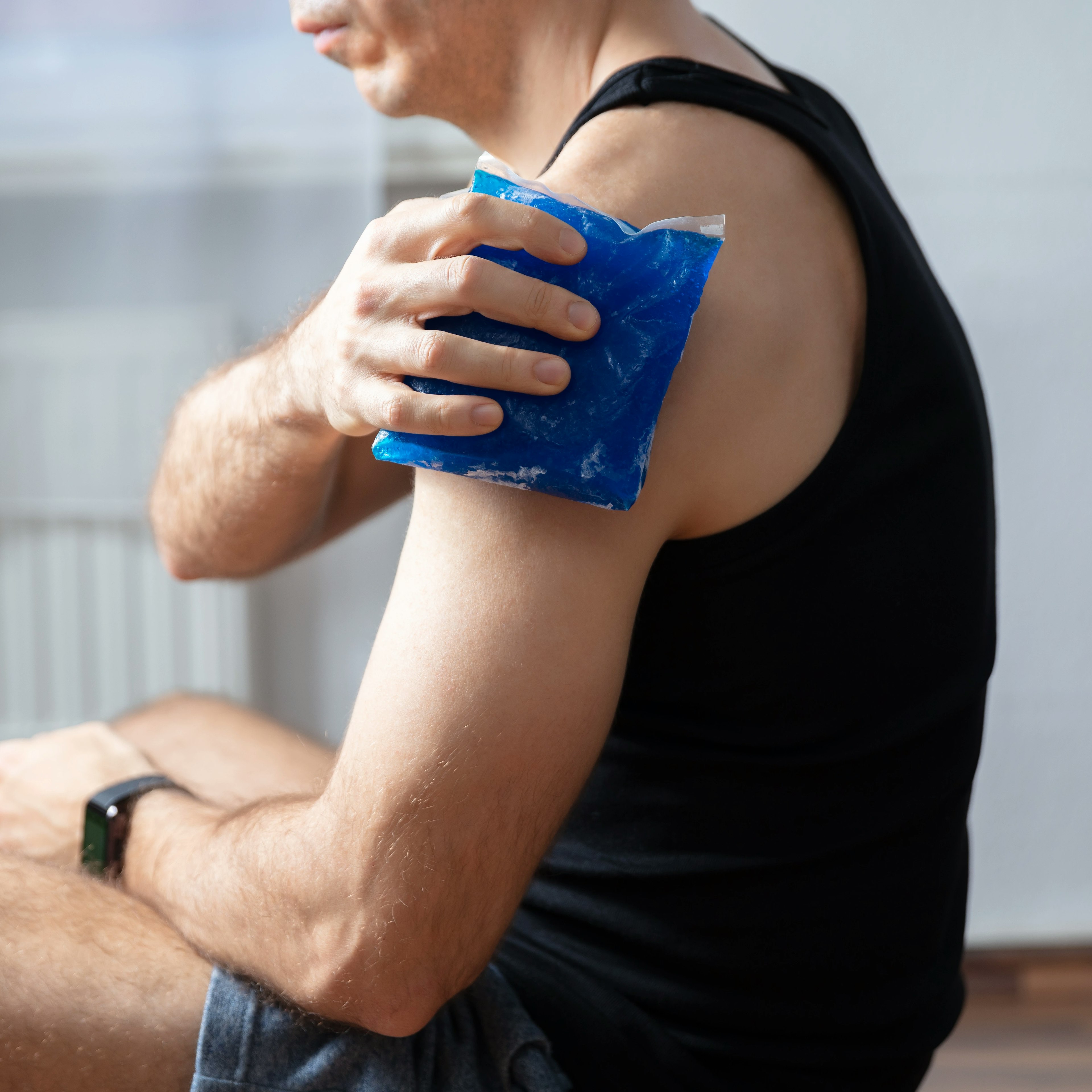 A man is icing his injury on his upper arm. 