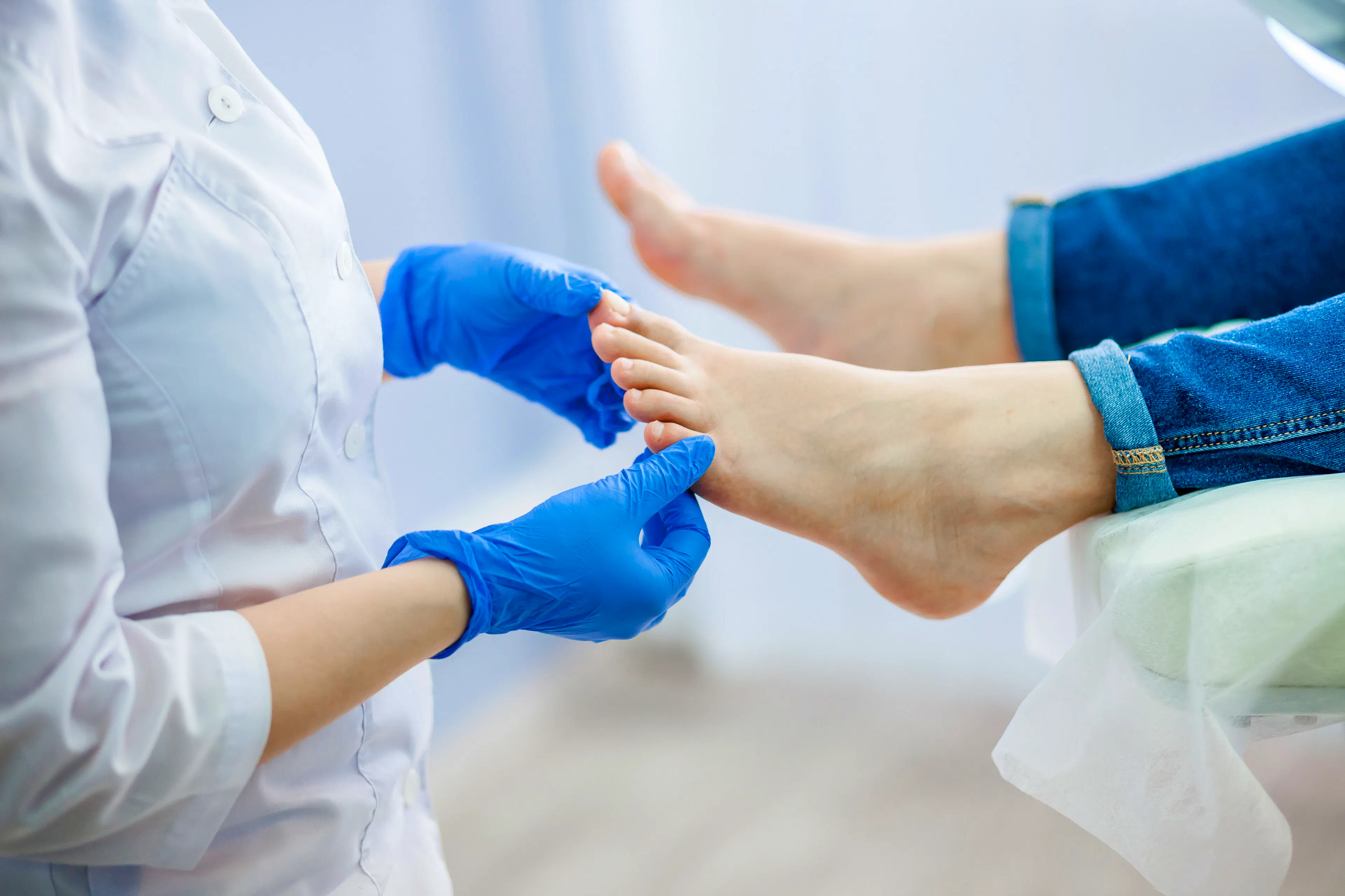 A doctor wearing gloves is checking a patient's feet. 