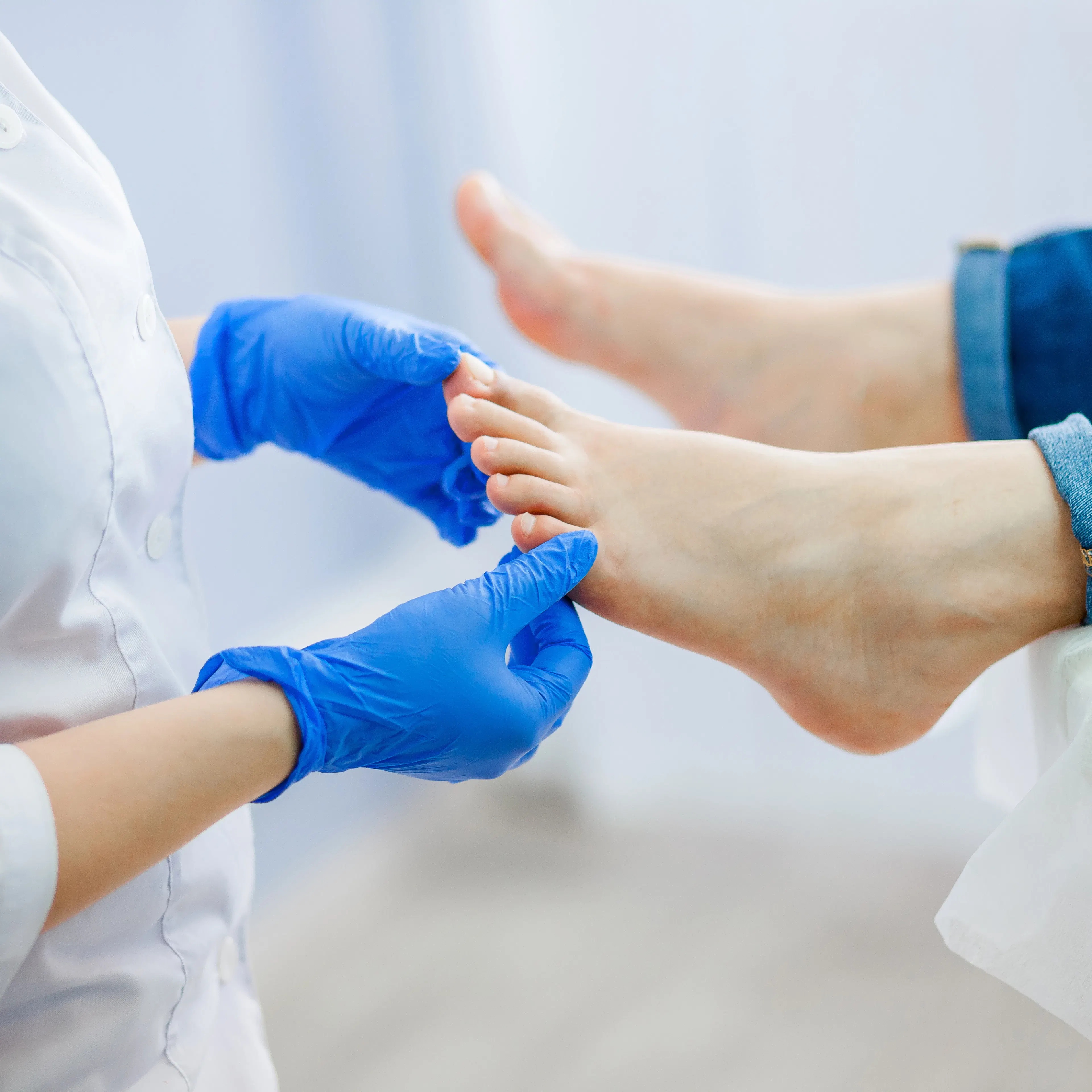 A doctor wearing gloves is checking a patient's feet. 