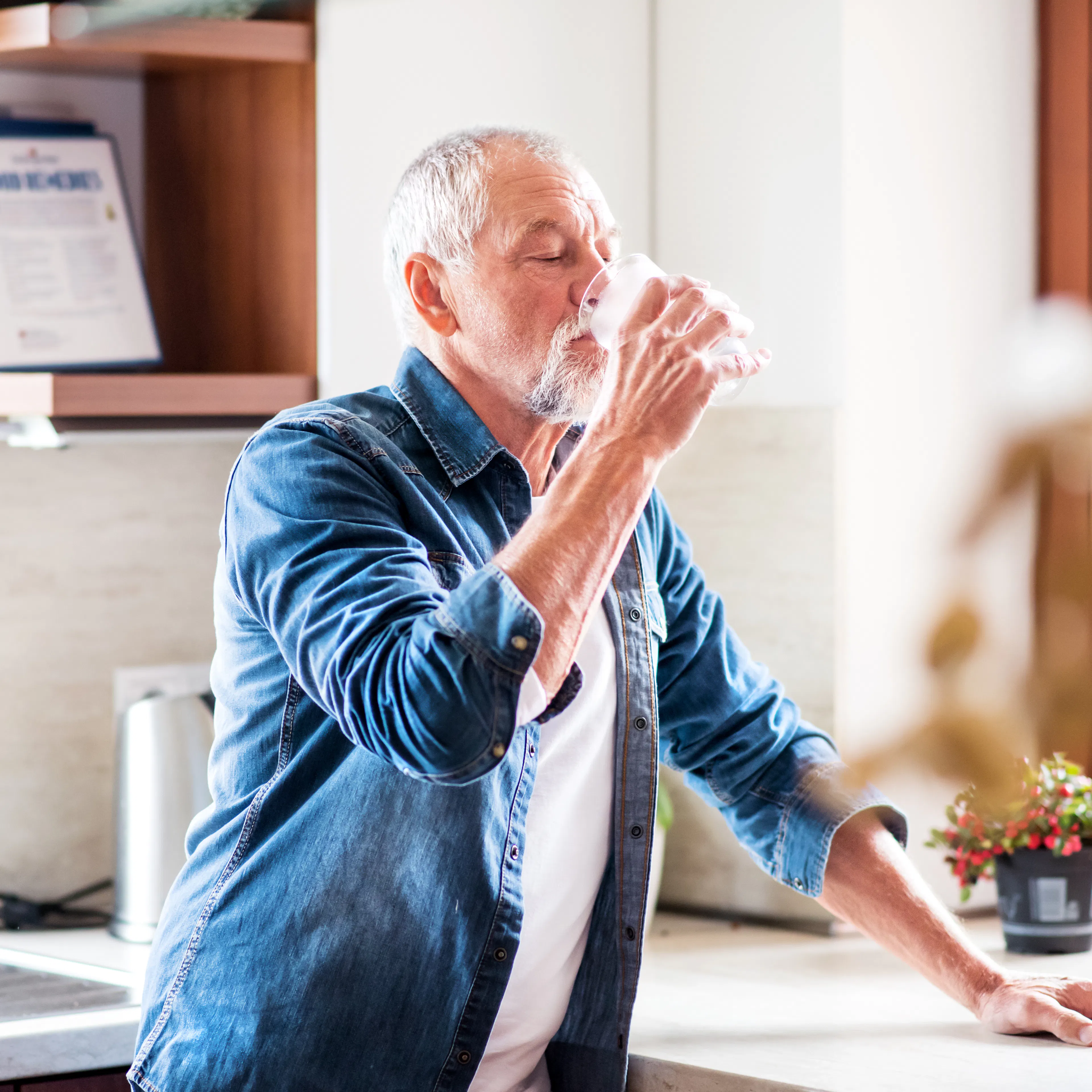 An elderly man is drinking water for colonoscopy preparation. 