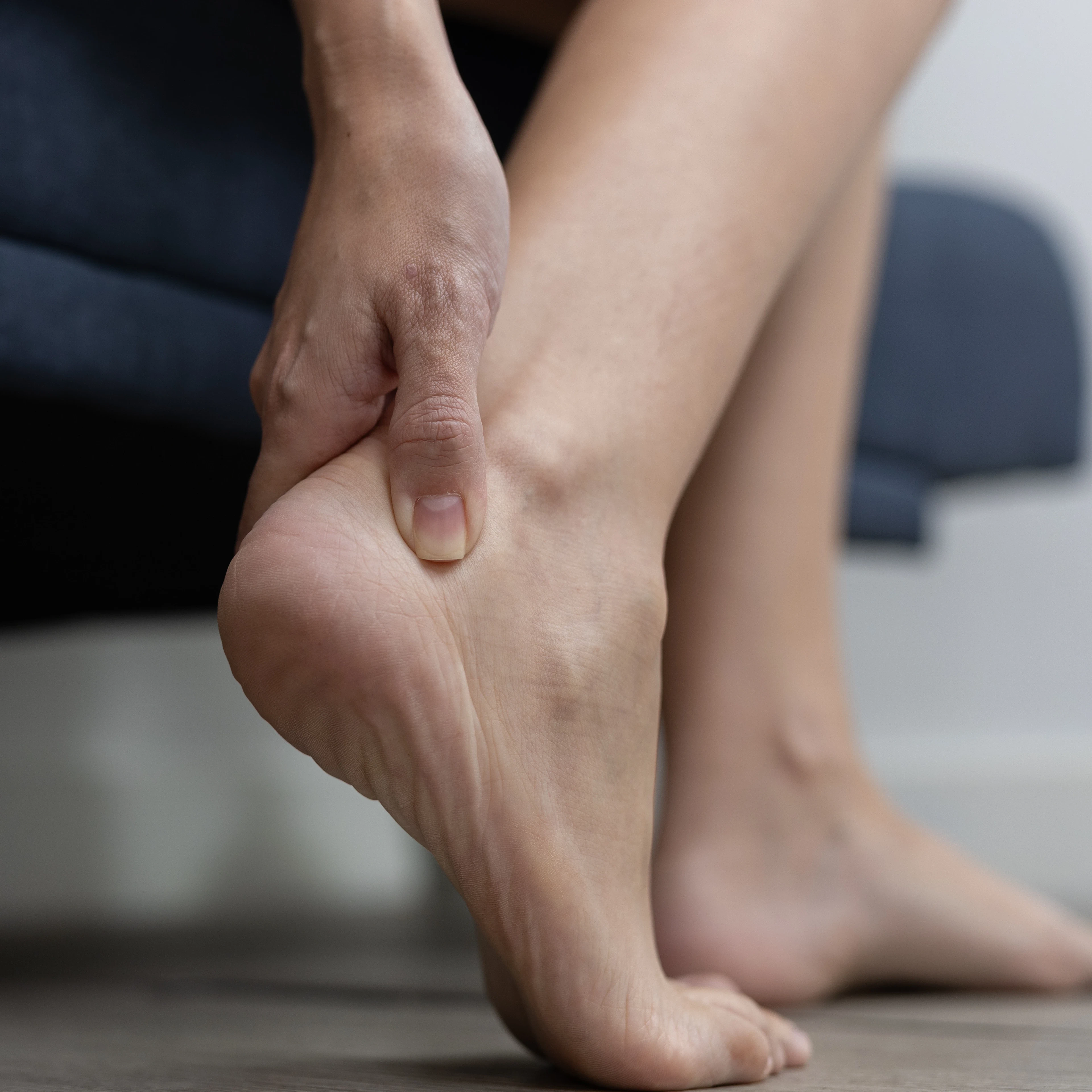 A close-up of a person's foot, showing them grabbing their ankle in pain. 