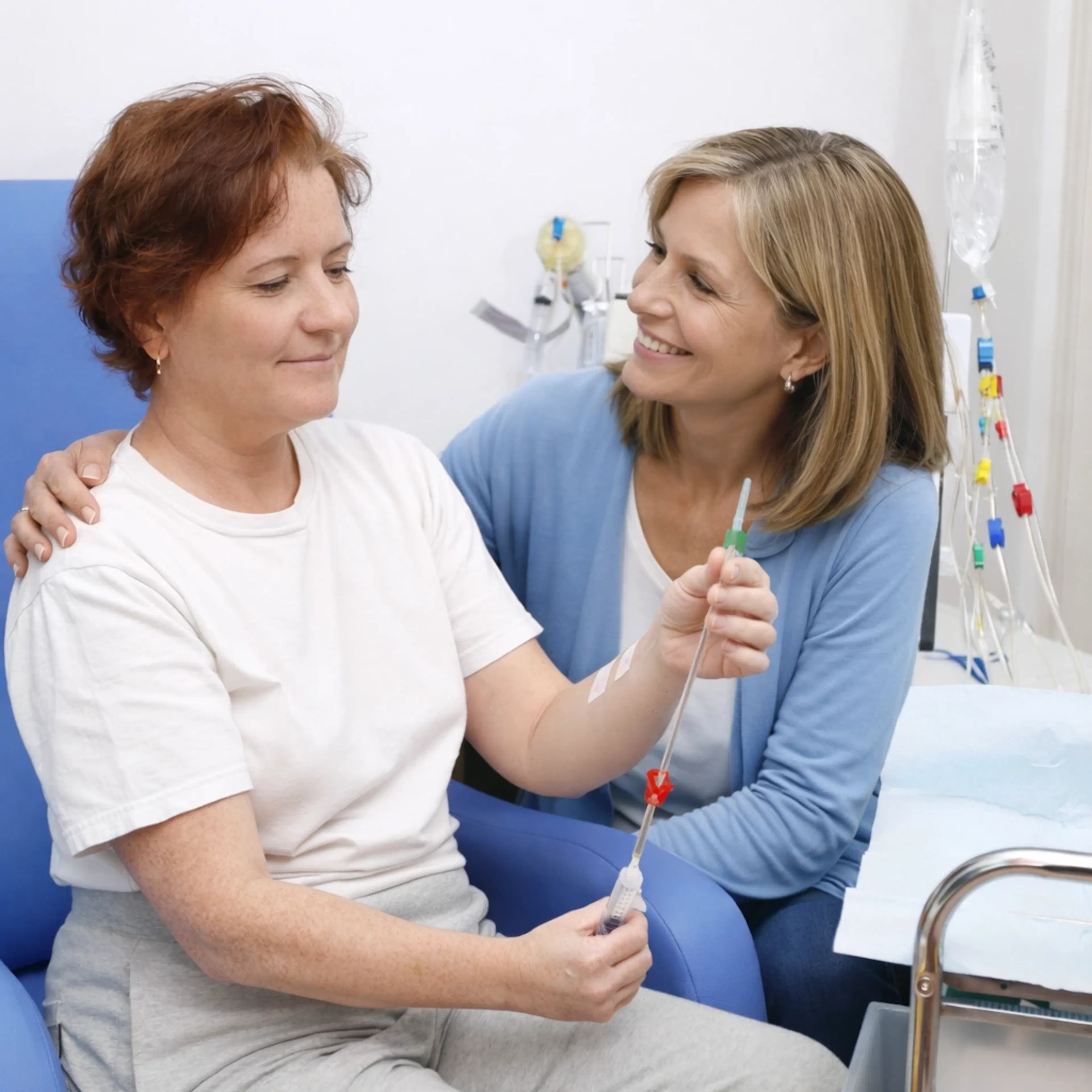 A middle-aged woman is doing home dialysis treatment. She is accompanied by a woman for moral support. 