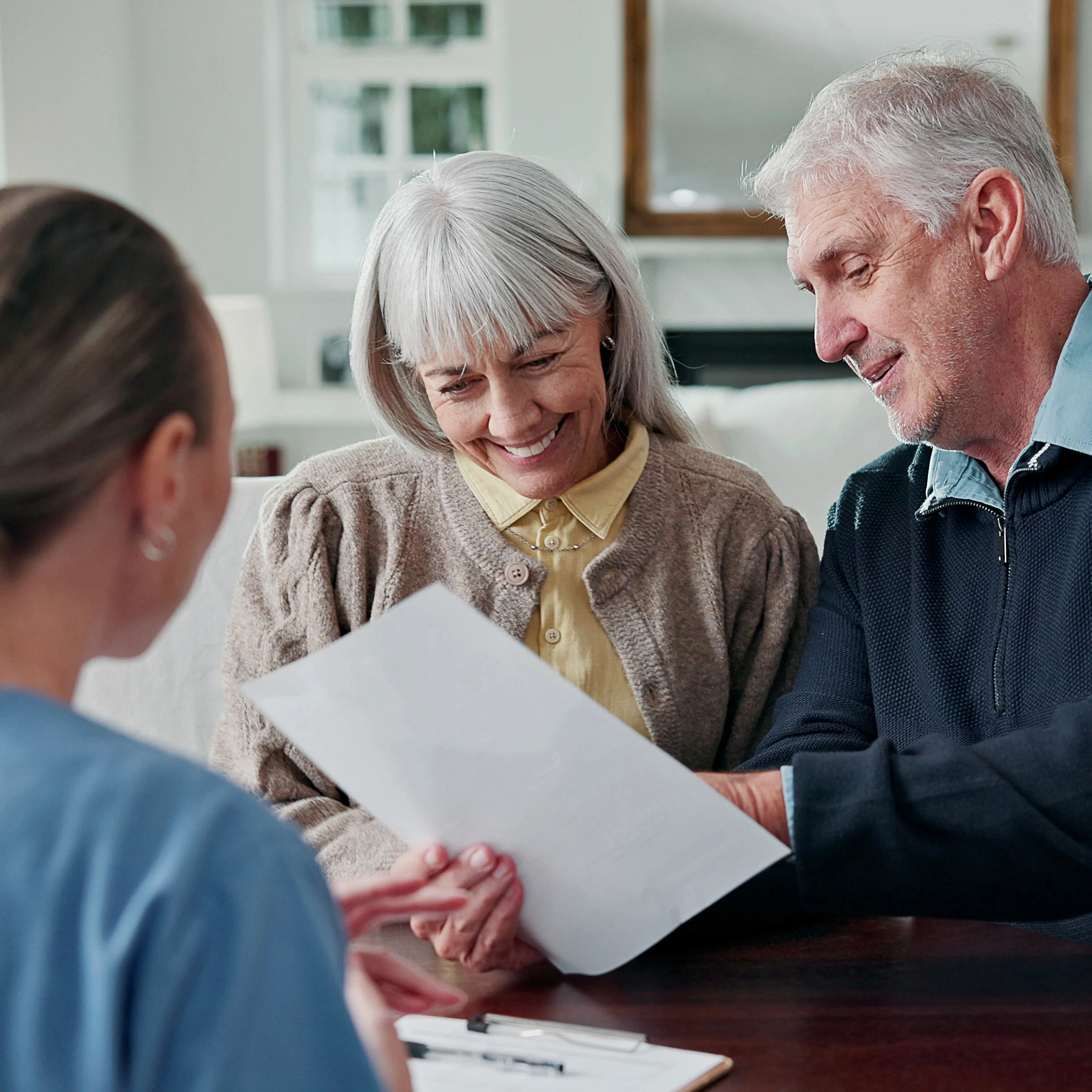 An elderly couple is reviewing health insurance paperwork with a helpful worker.