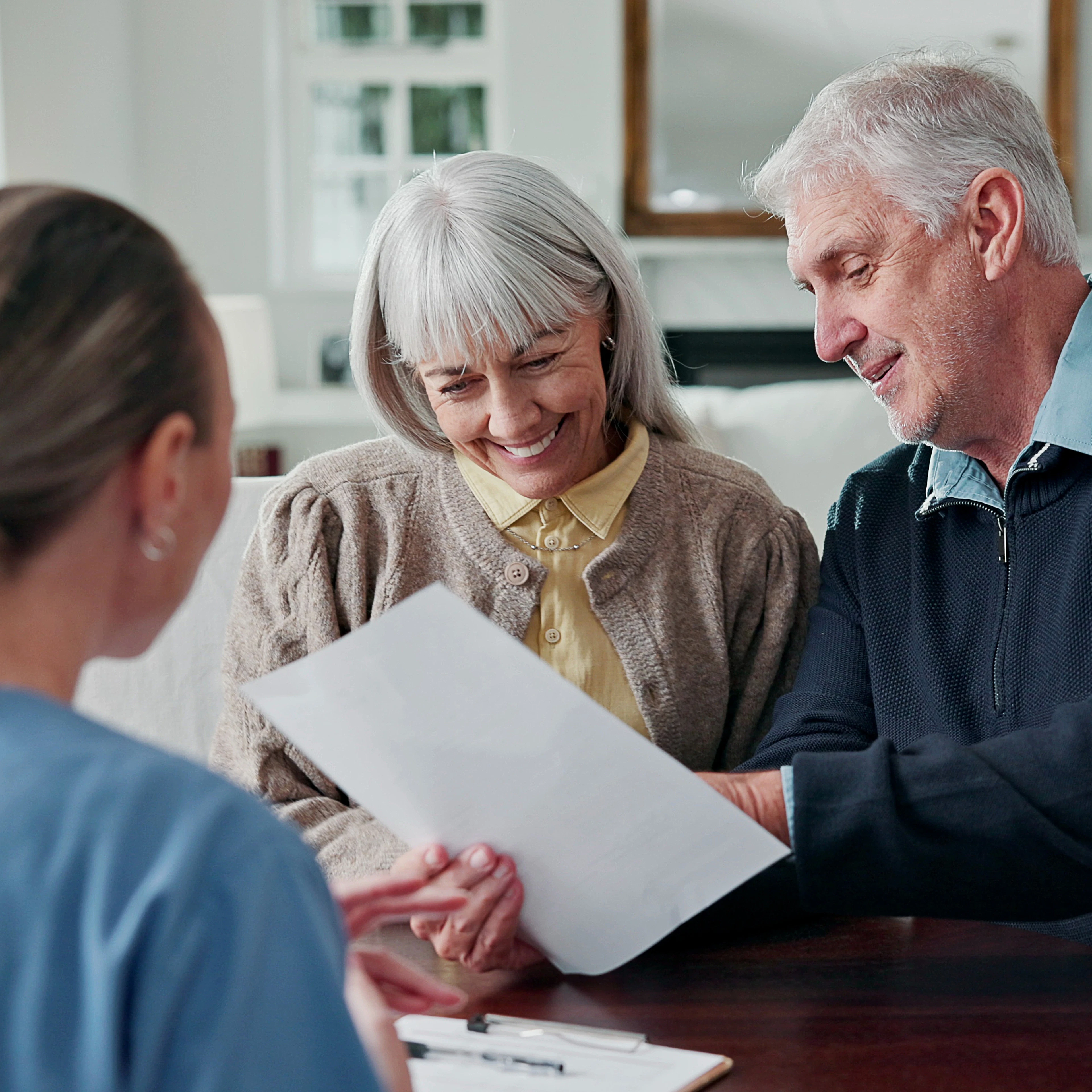 An elderly couple is reviewing health insurance paperwork with a helpful worker.