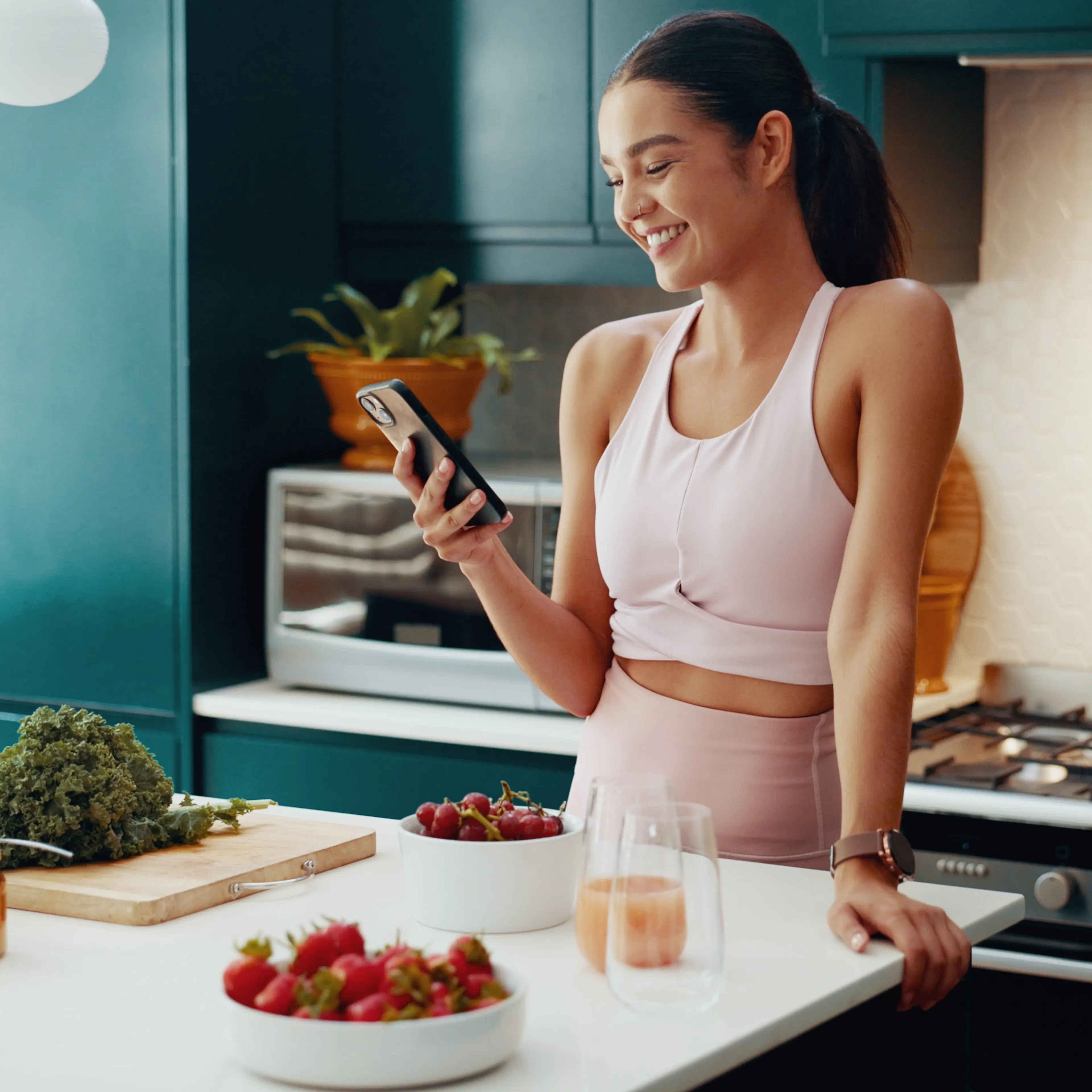 A fit woman is looking at her smartphone while preparing food, presumably to track her nutrition. 