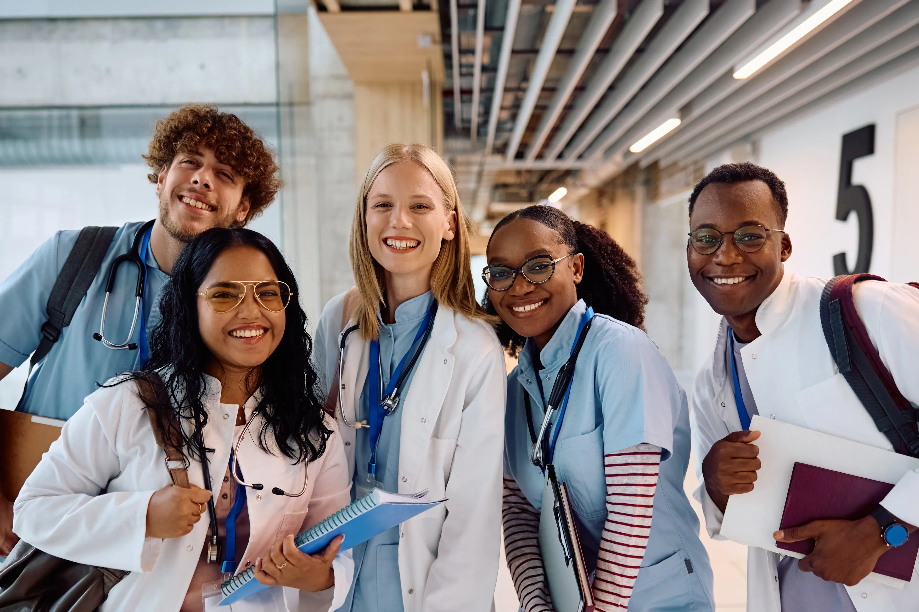 A group of students in scrubs and white coats posing for a group photo.