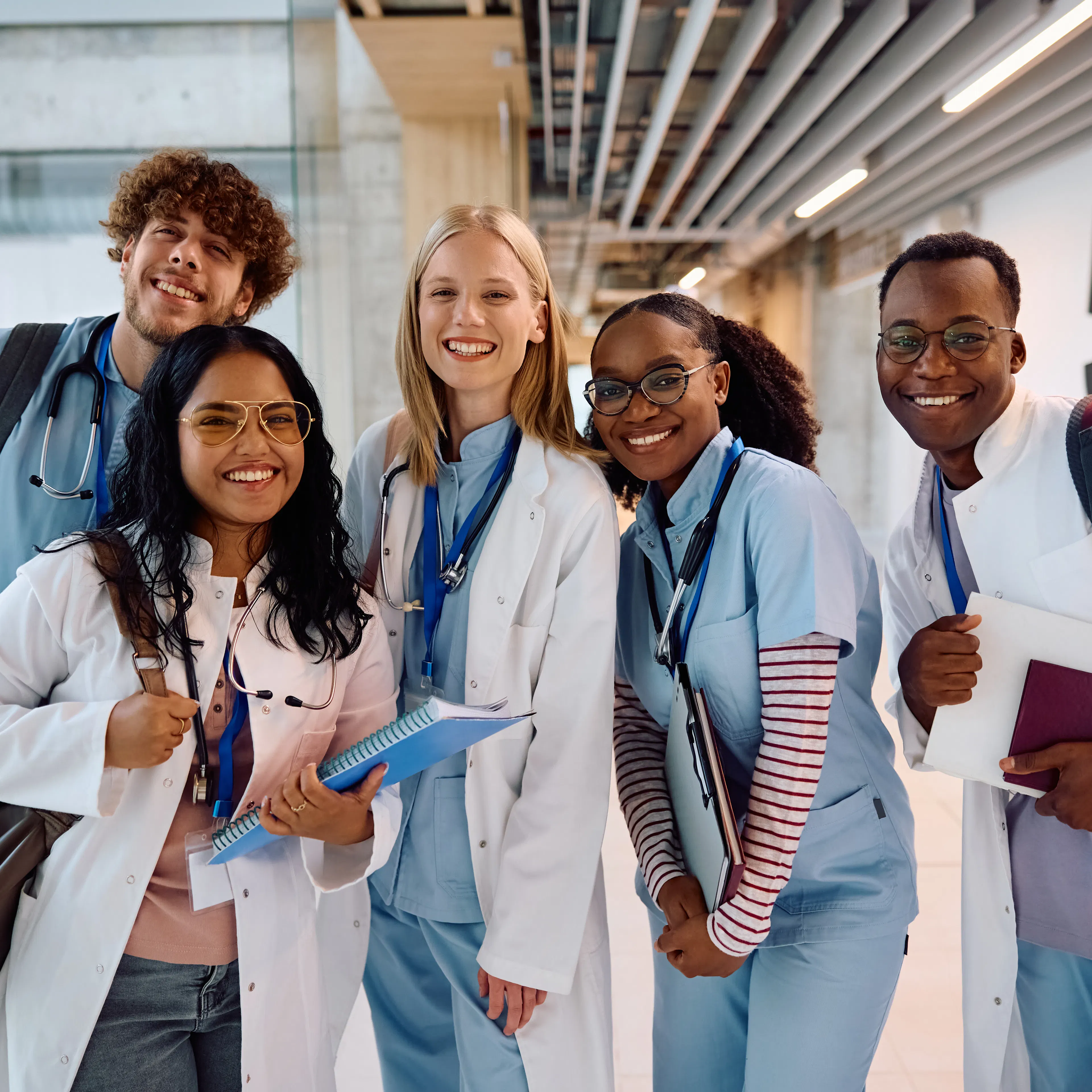 A group of students in scrubs and white coats posing for a group photo. 