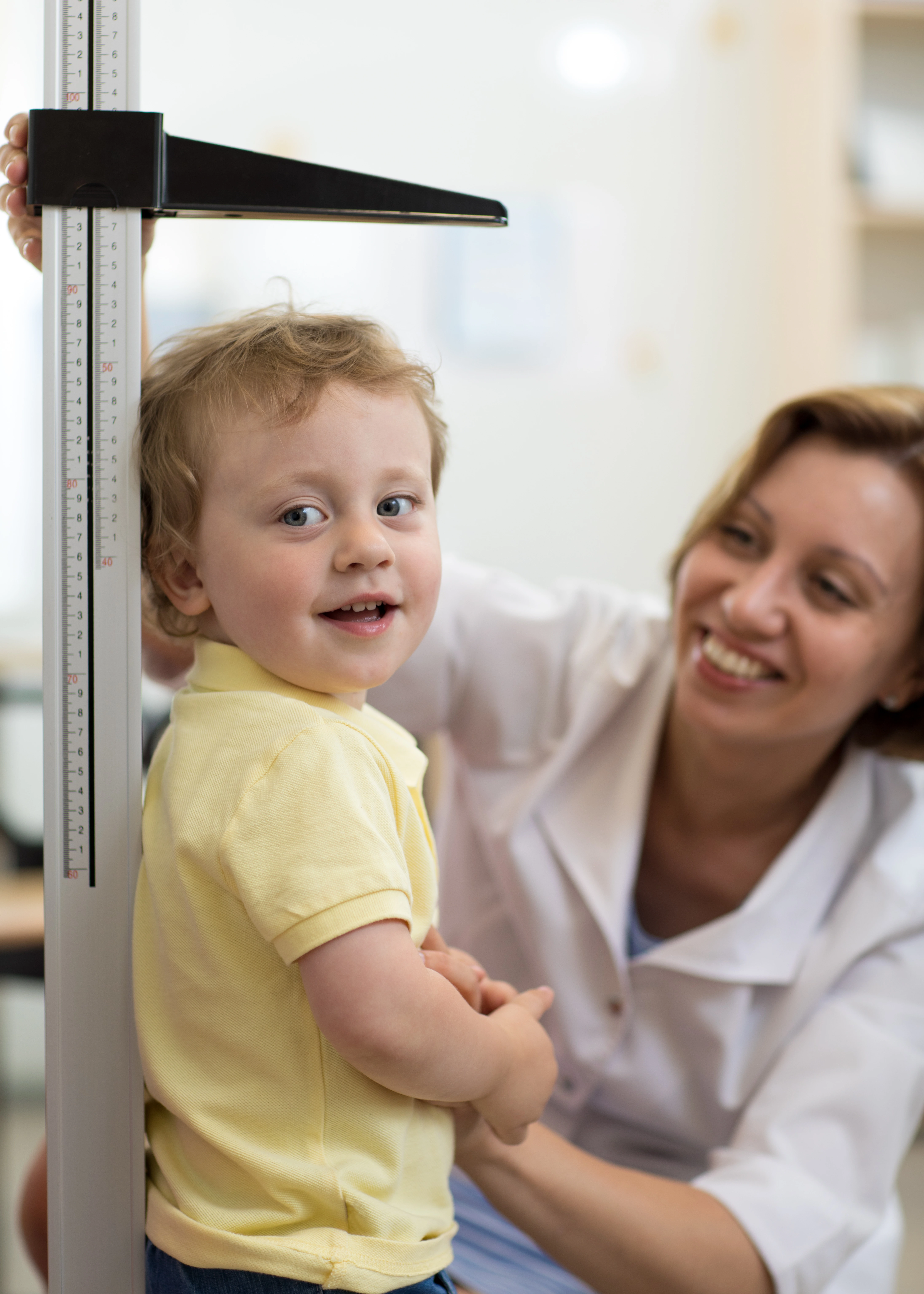 A little boy's height is being measured for a school physical or annual wellness exam at the doctor's clinic.