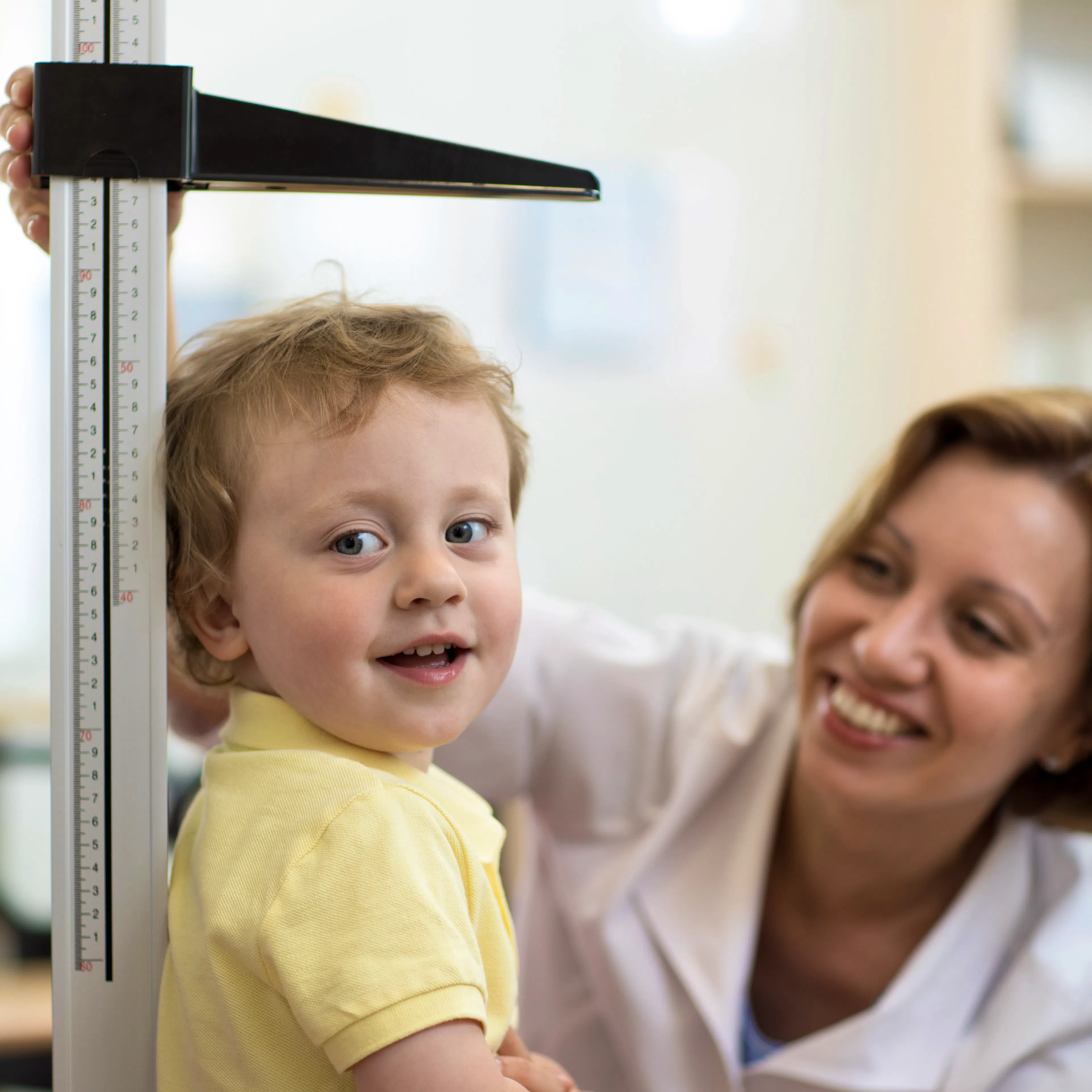 A little boy's height is being measured for a school physical or annual wellness exam at the doctor's clinic.
