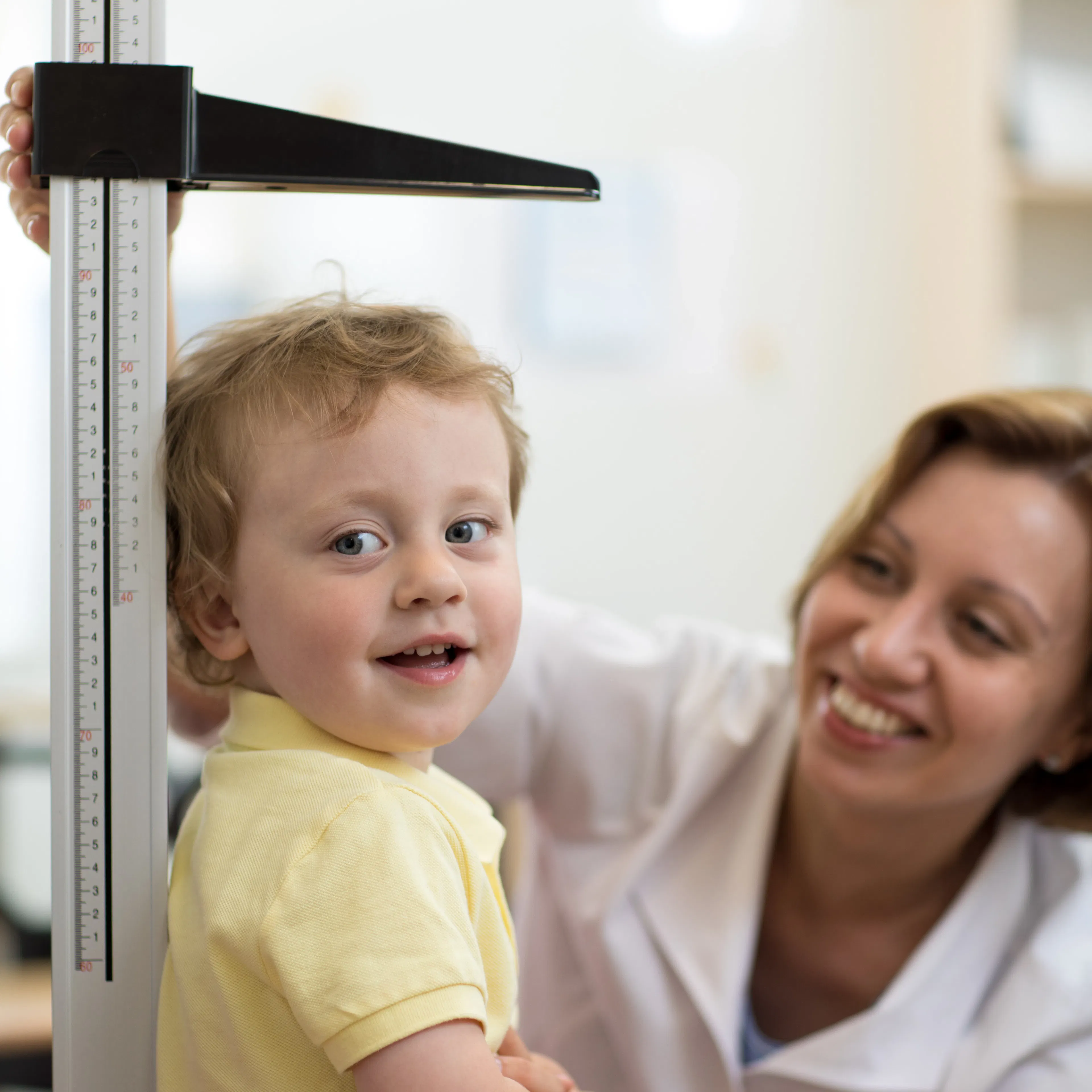 A little boy's height is being measured for a school physical or annual wellness exam at the doctor's clinic.