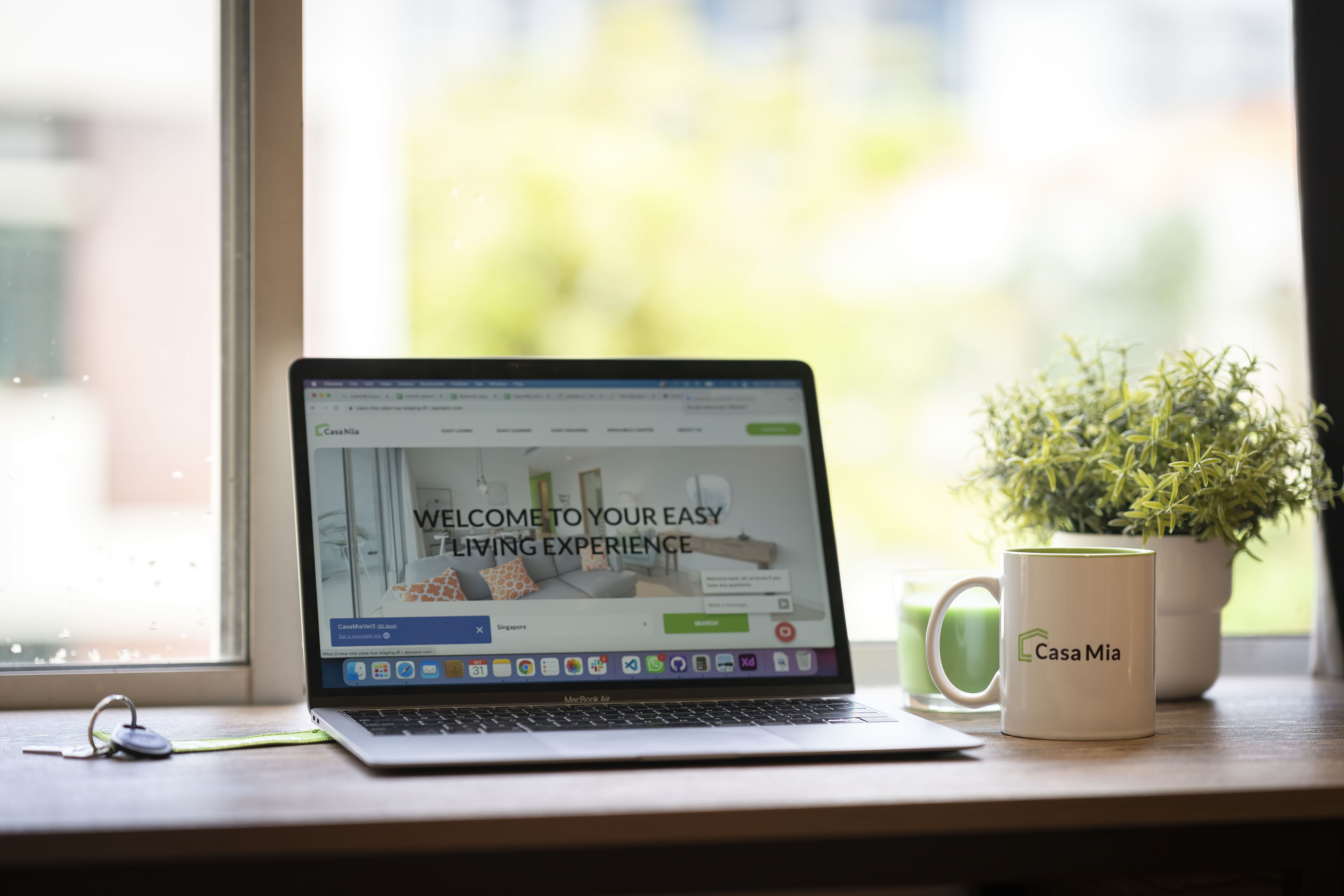 A laptop with a Casa Mia mug next to it