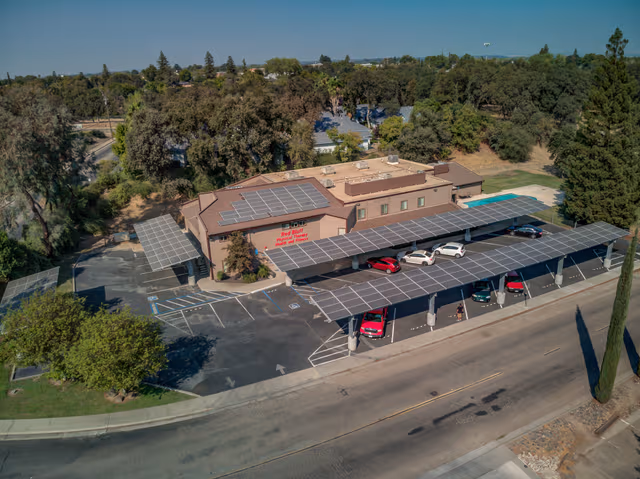 Company building with carports equipped with solar panels, supported by galvanized steel structures providing durable corrosion protection by Coatinc US.
