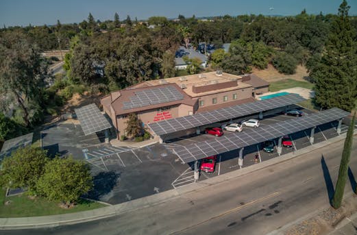 Company building with carports equipped with solar panels, supported by galvanized steel structures providing durable corrosion protection by Coatinc US.