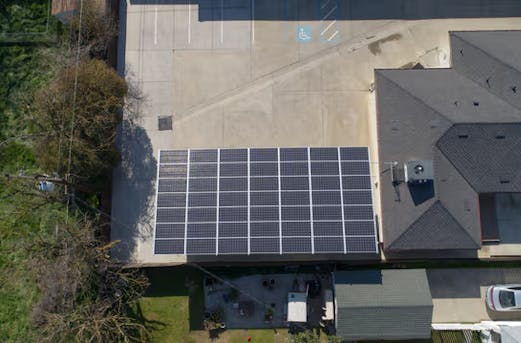 House with a large carport topped with solar panels, supported by galvanized steel structures for durable corrosion protection by Coatinc US.